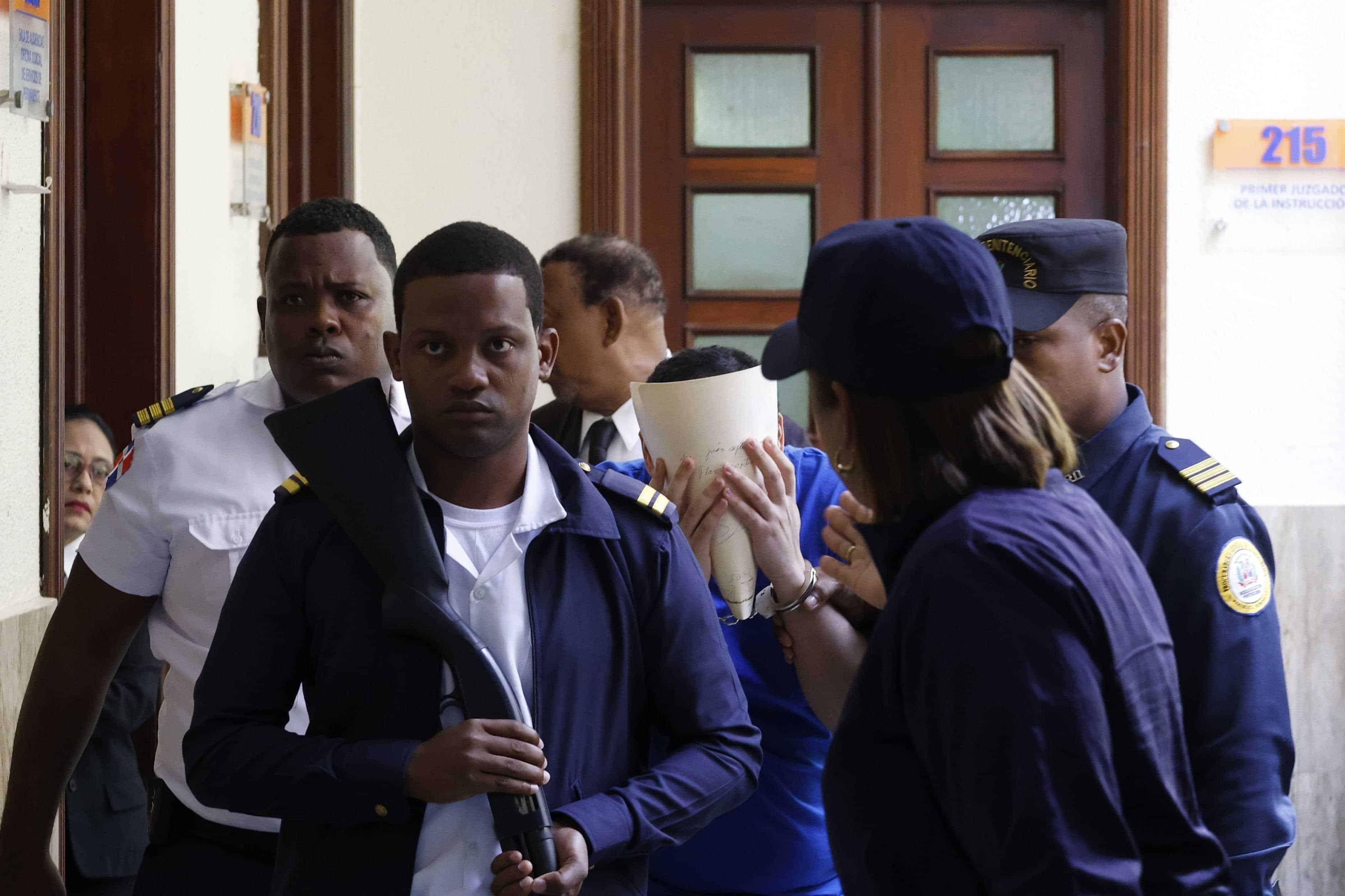 El joven Ronald Familia Frías, se cubre el rostro al salir de la Oficina de Atención Permanente del Palacio de Justicia del Distrito Nacional.