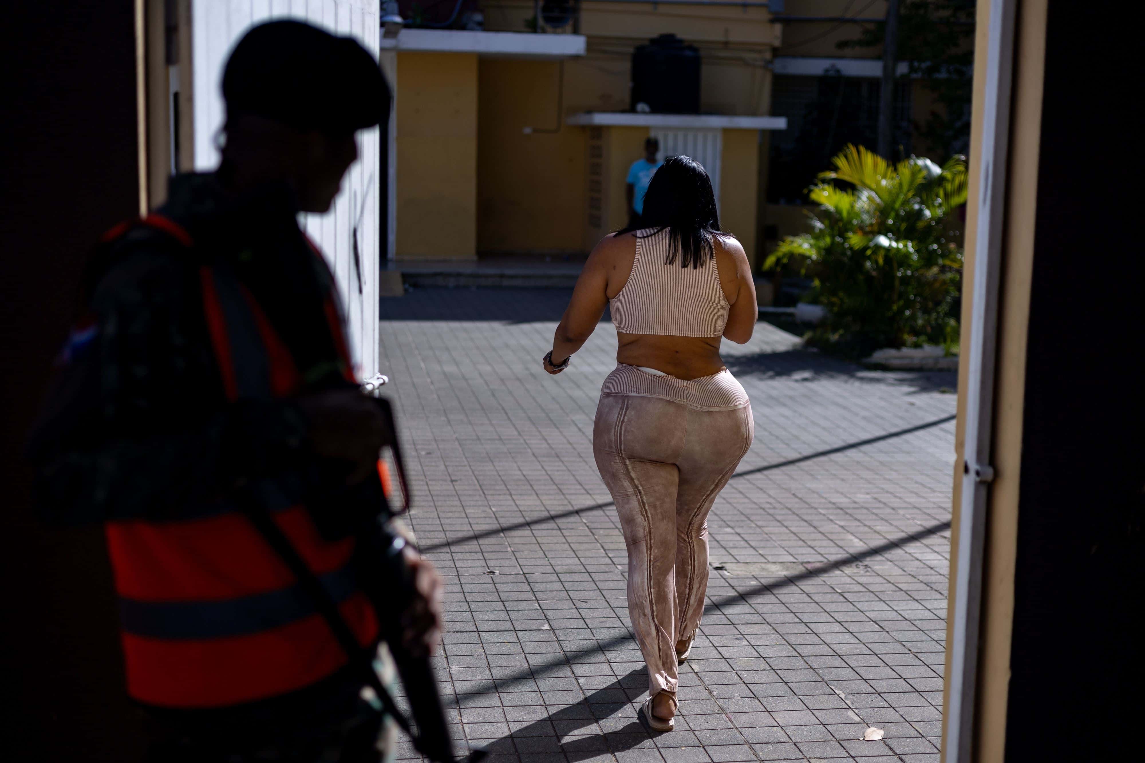 Un efectivo de la Policía Militar Electoral mira fijamente el cuerpo curvilíneo de una ciudadana que acude a ejercer su derecho al voto en las elecciones generales de República Dominicana.