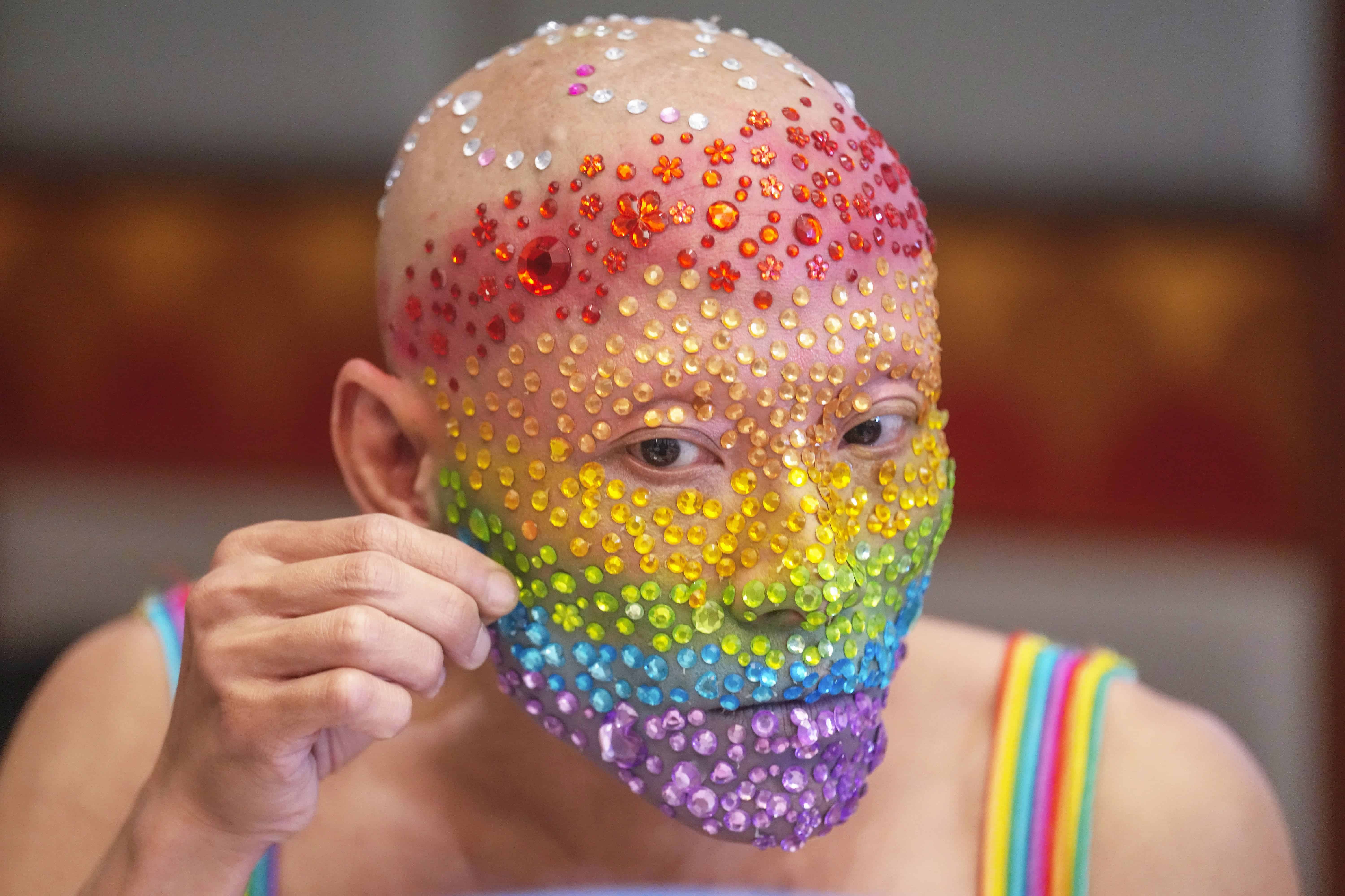 Un participante LGBTQ decora su rostro antes de una conferencia de prensa en Bangkok, Tailandia, el lunes 20 de mayo de 2024.
