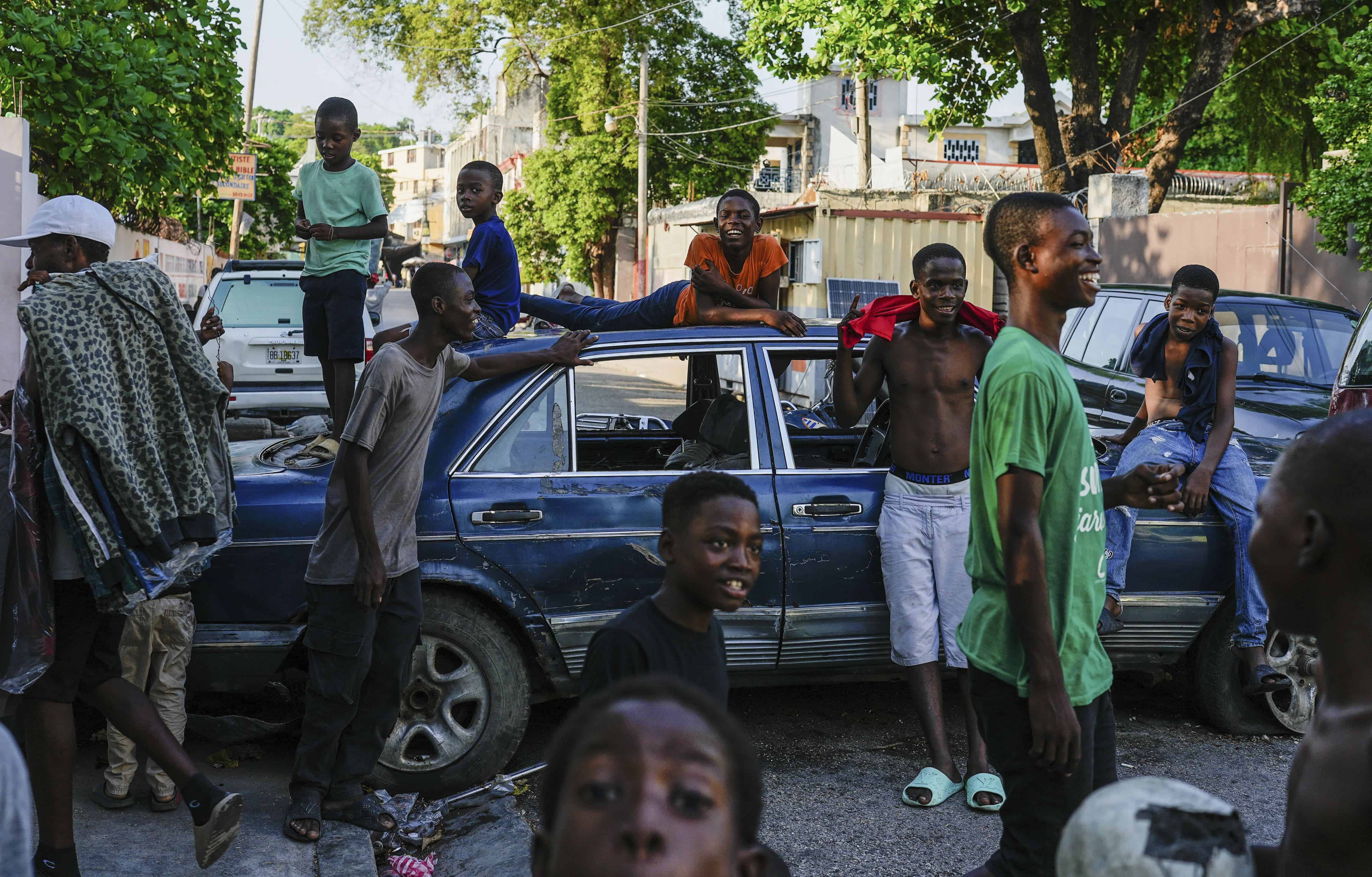 Los jóvenes pasan el rato cerca de los automóviles que sirven como barricadas en las calles colocadas por los residentes para disuadir a las pandillas de ingresar a su vecindario, en el centro de Puerto Príncipe, Haití, el 17 de mayo de 2024.