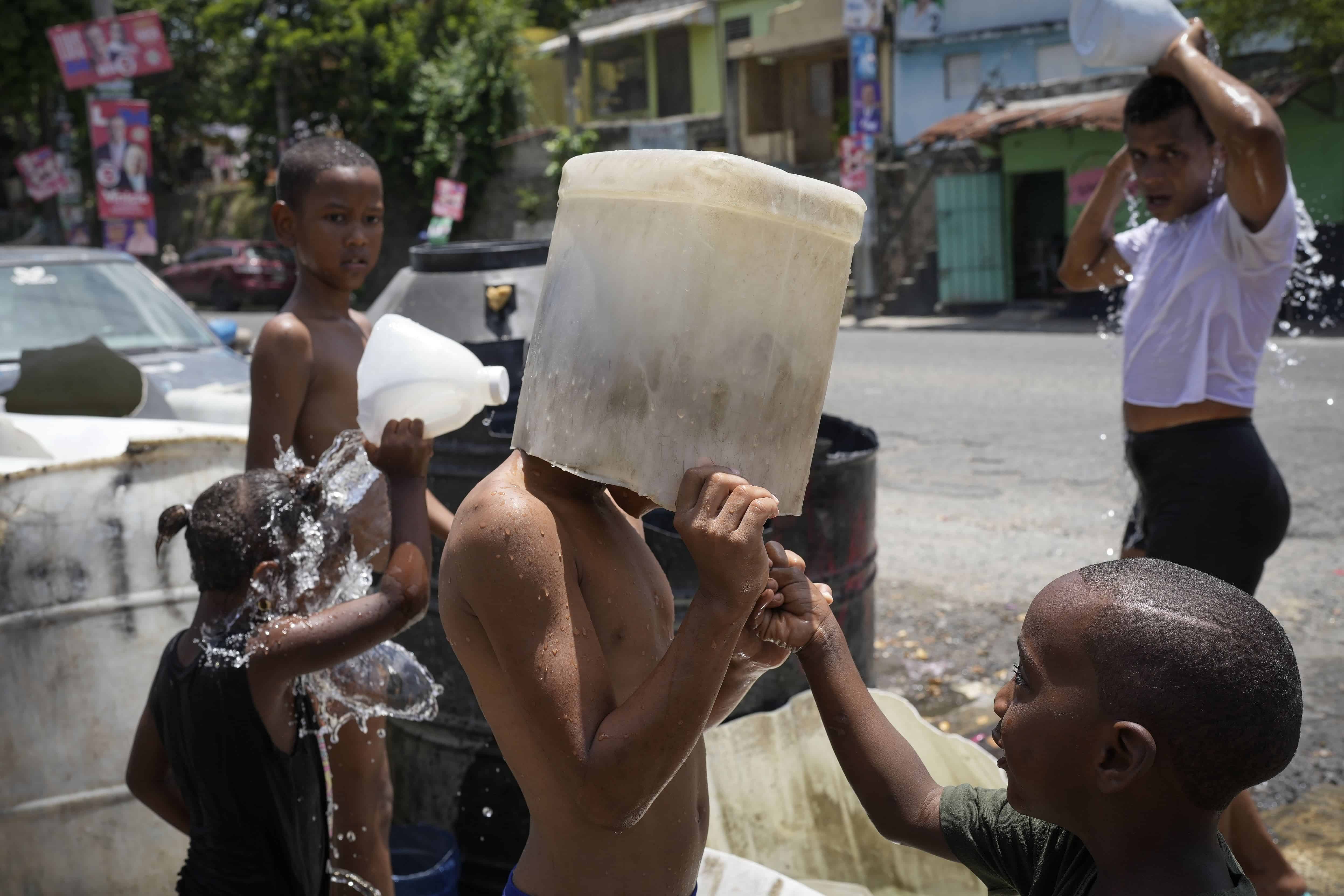 Un niño se cubre la cabeza con un balde en el barrio Los Guandules de Santo Domingo, República Dominicana, el 20 de mayo de 2024.