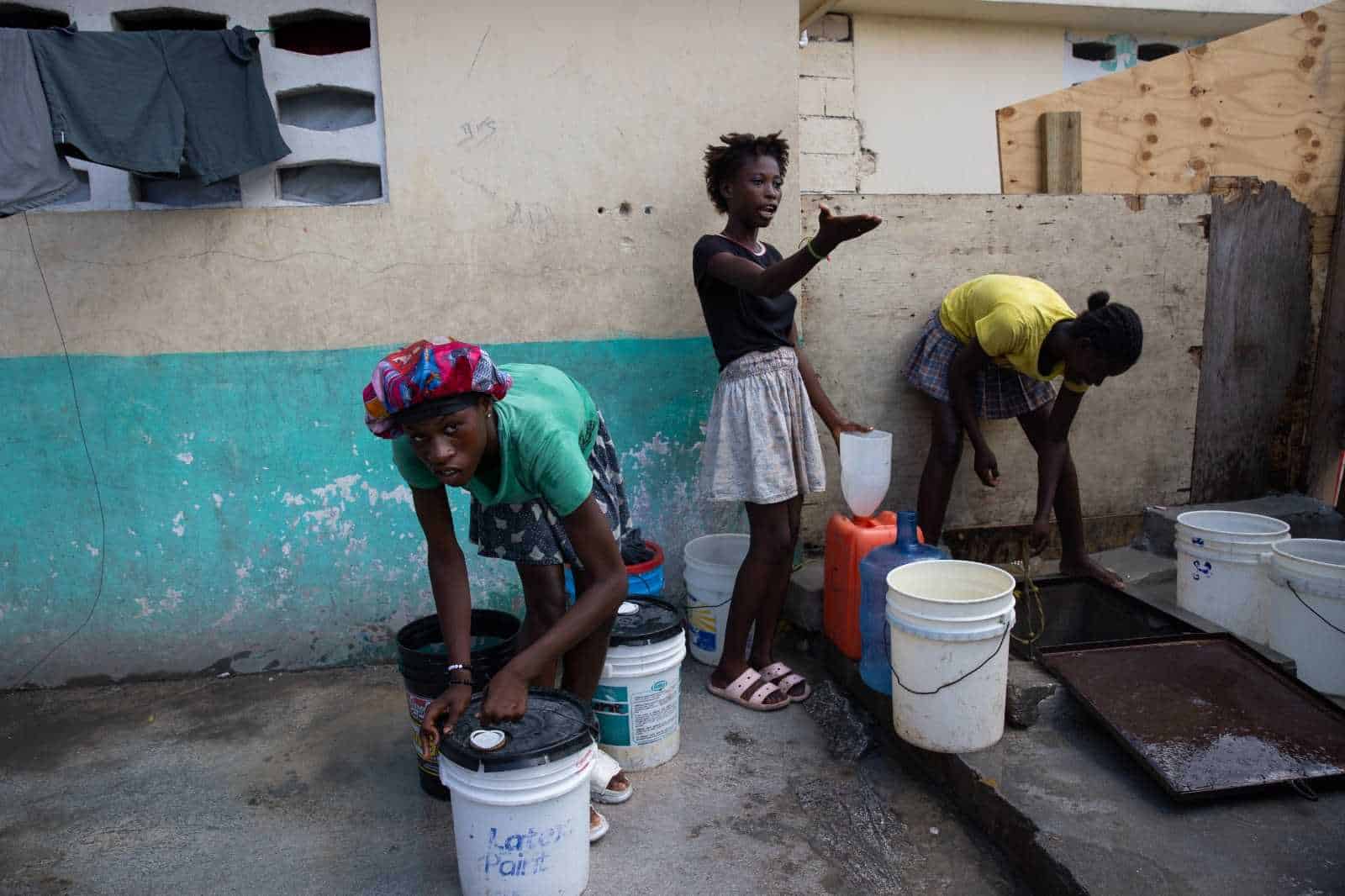 Jóvenes sacan agua de un pozo en el campamento de refugiados Carrade, este sábado en Puerto Príncipe (Haití). 