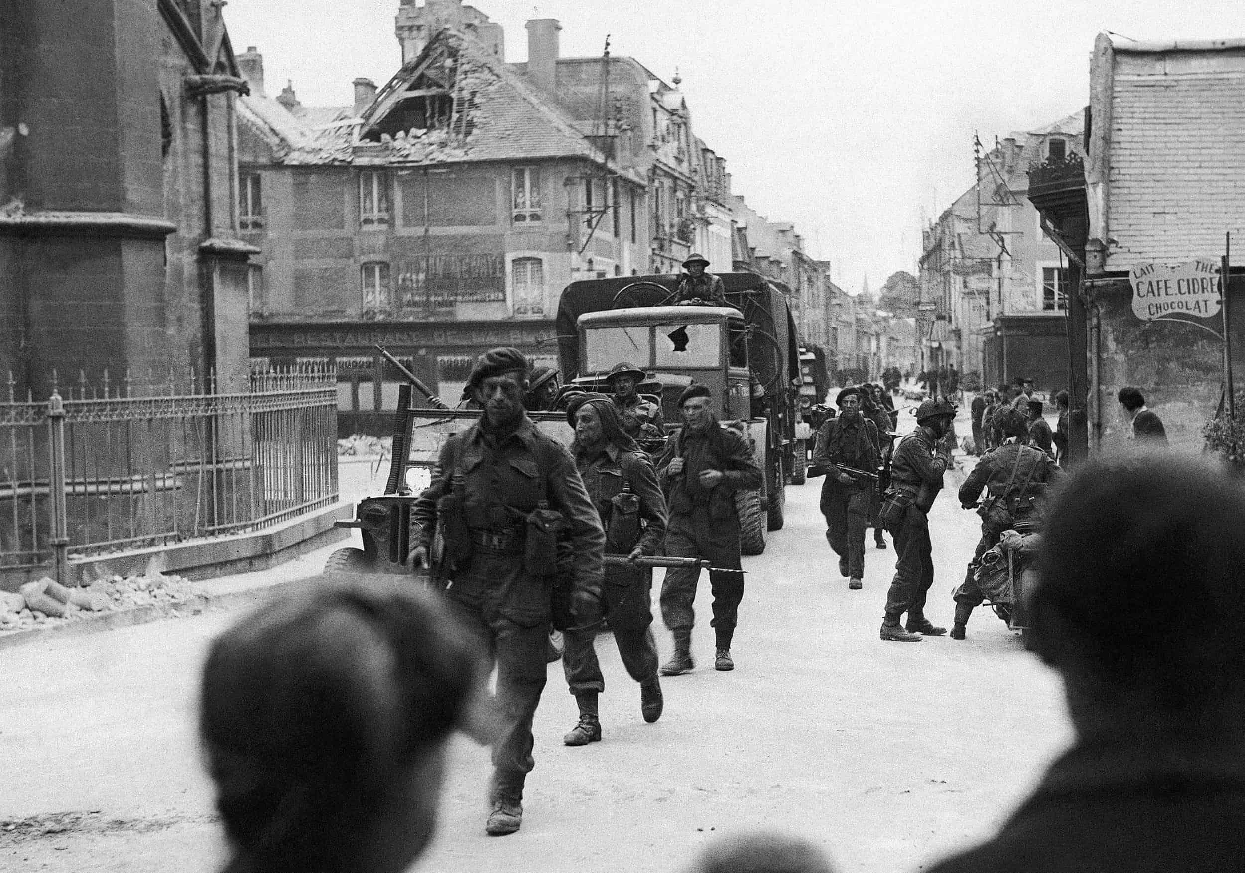ARCHIVO - Comandos británicos pasan por las calles de una ciudad cerca de Caen, en Normandía, Francia, el 6 de junio de 1944. Tras los desembarcos iniciales en la costa francesa, las tropas aliadas inmediatamente comenzaron a avanzar hacia el interior. Al pasar por los pueblos de Normandía, sus habitantes les dieron una cálida bienvenida.