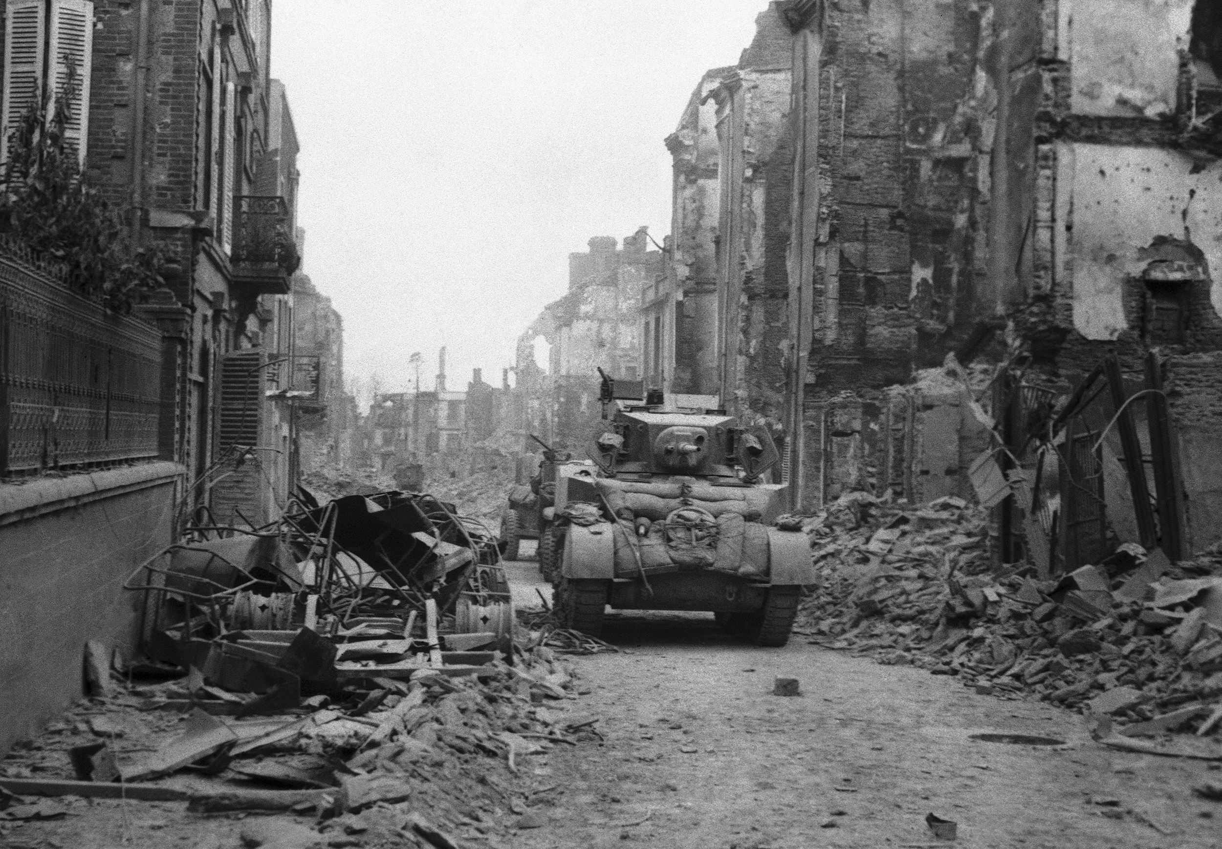 ARCHIVO - Un tanque británico avanza por una calle, con la batalla aún en curso, mientras la ciudad todavía está rodeada de armas nazis que continuamente lanzan proyectiles a la calle, en St. Lo, Normandía, Francia, el 20 de junio de 1944.