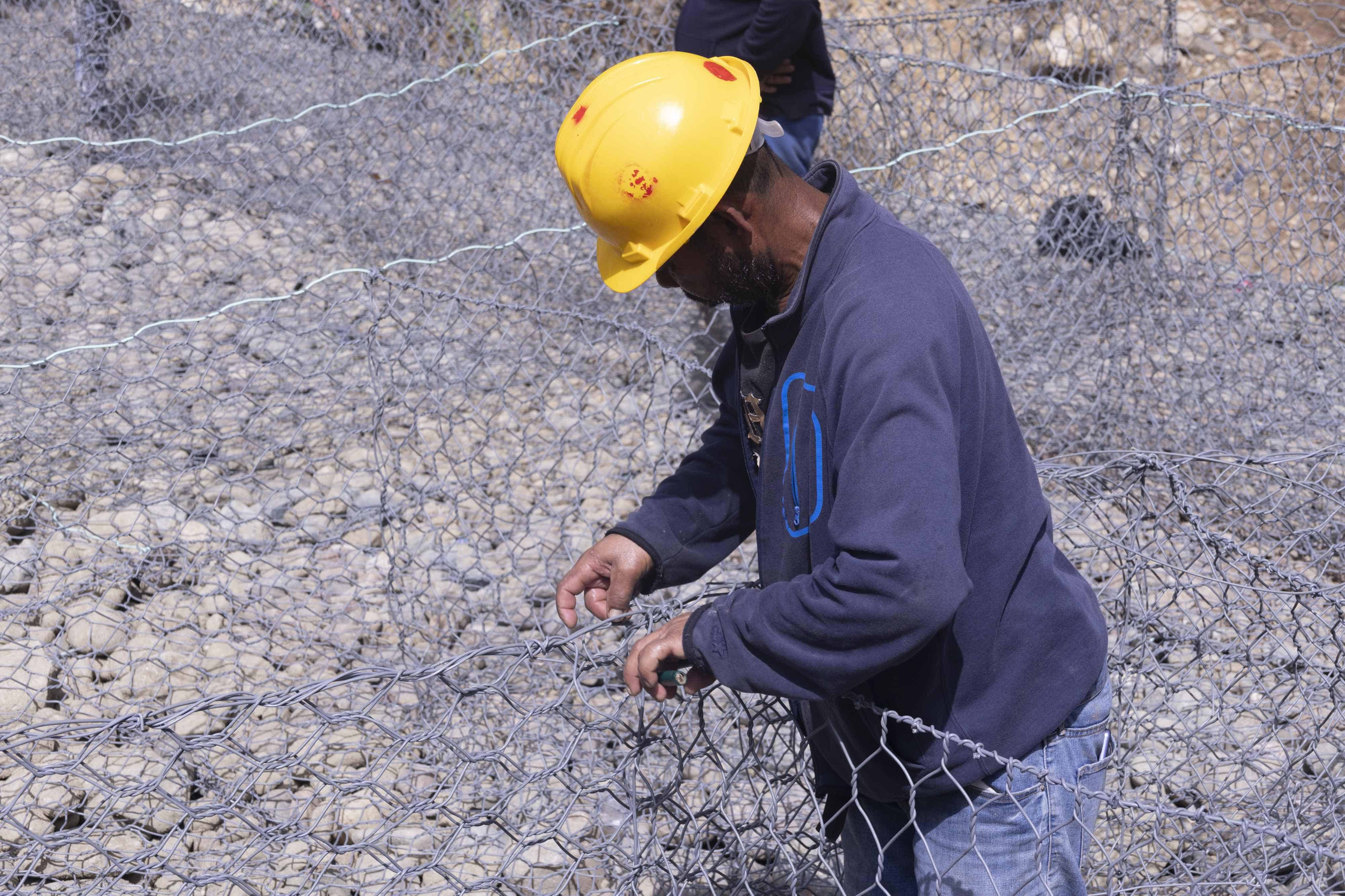 Trabajadores construyen el muro de gaviones.