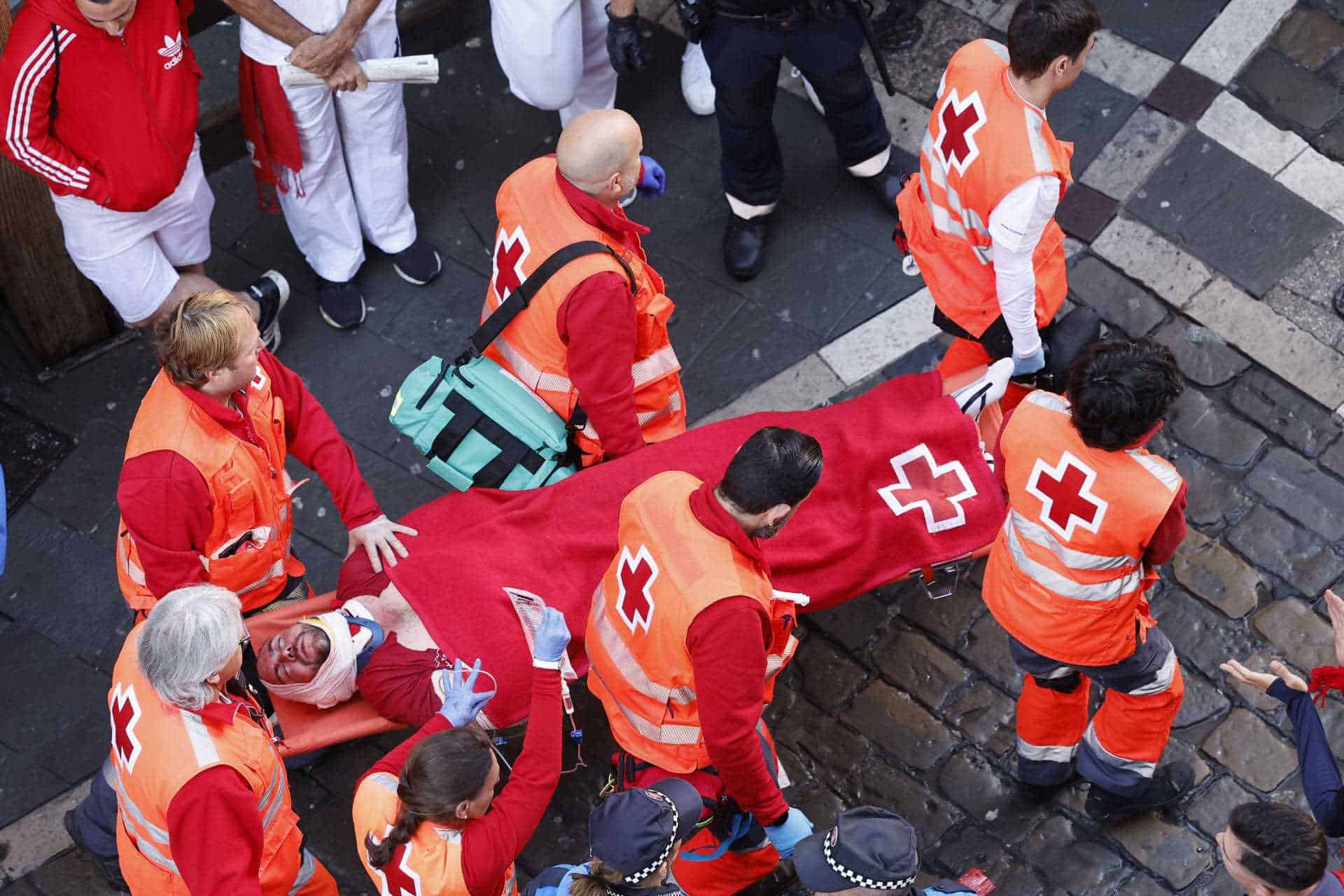 Miembros de los servicios sanitarios evacúan a un herido en la calle Estafeta durante el primer encierro de los Sanfermines en el Día de San Fermín