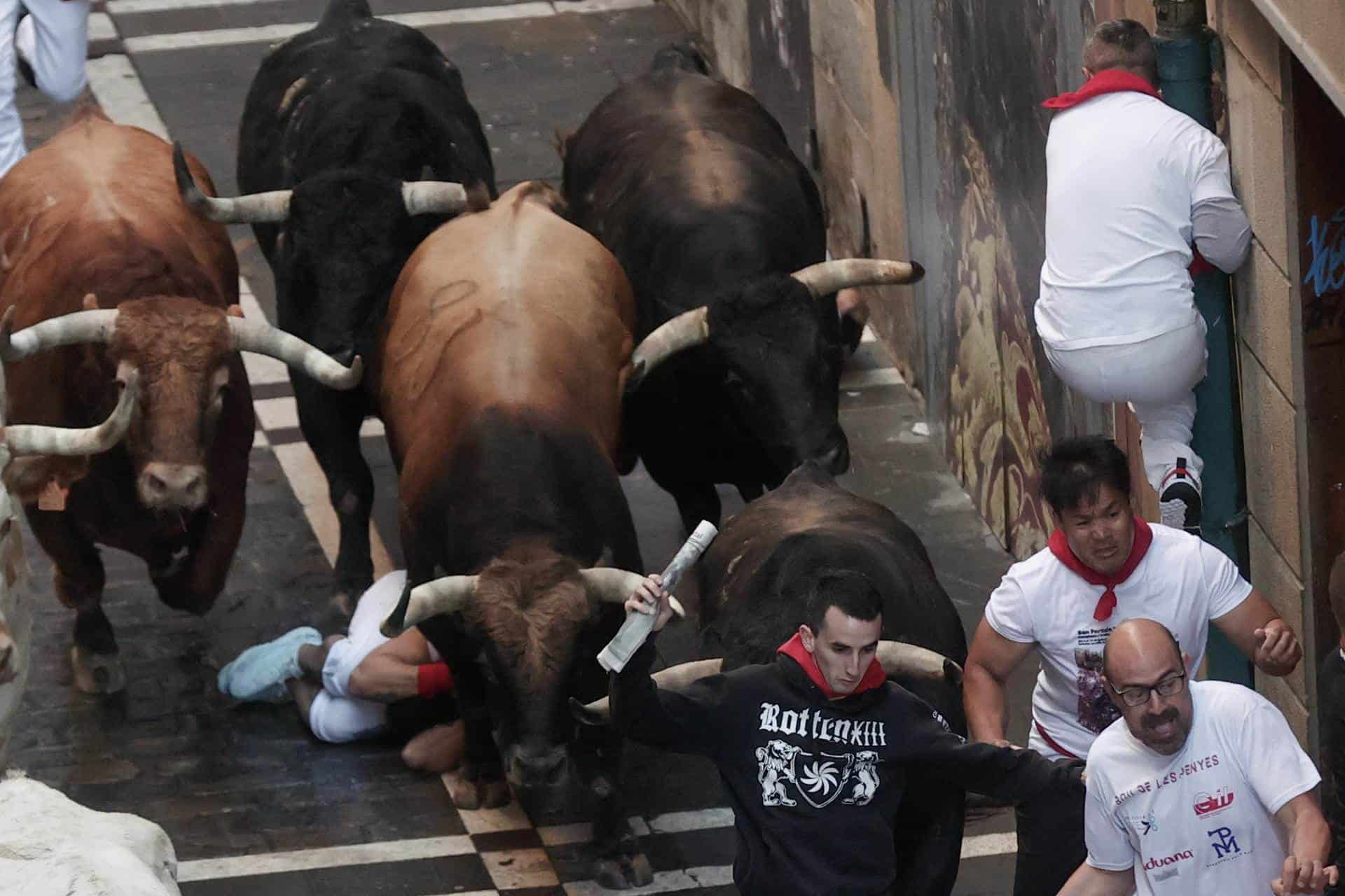 Los toros de la ganadería gaditana de La Palmosilla arrollan a un corredor en el tramo del ayuntamiento este domingo durante el primer encierro de los Sanfermines en el Día de San Fermín