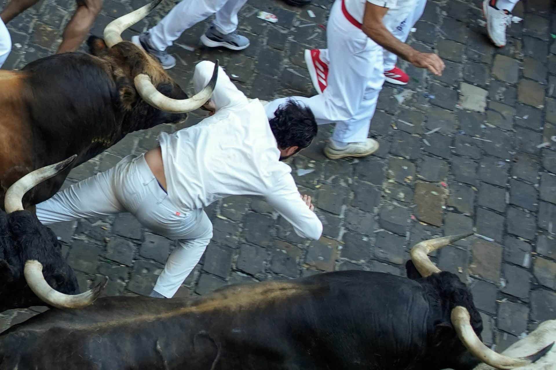 Los toros de la ganadería gaditana de La Palmosilla arrollan a un corredor en el tramo del ayuntamiento este domingo durante el primer encierro de los Sanfermines en el Día de San Fermín