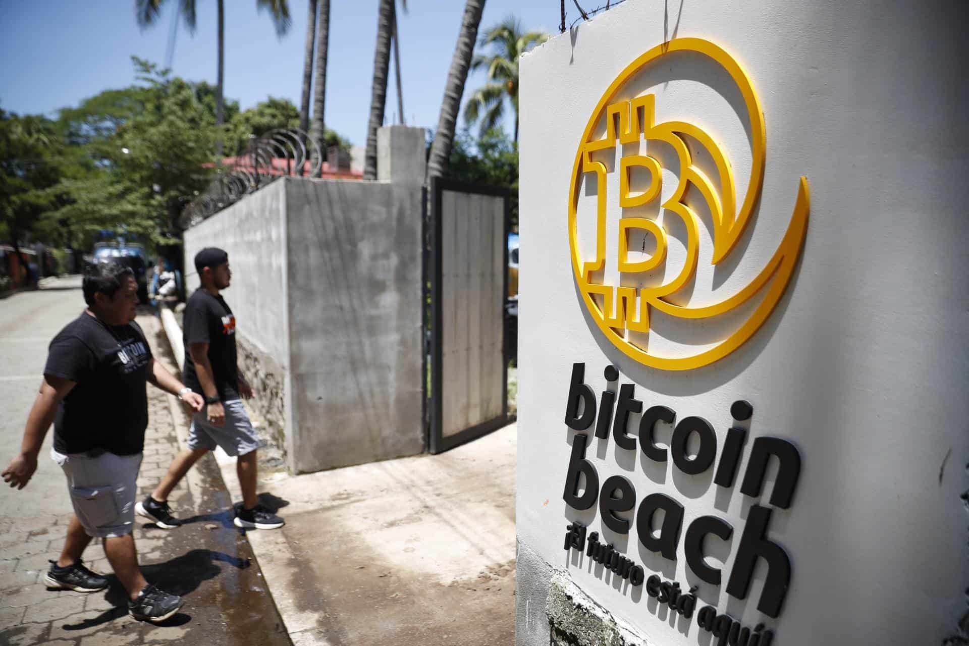 Dos promotores del uso del bitcóin caminan cerca de la playa El Zonte el 9 de julio de 2024, lugar donde empezó a utilizarse la criptomoneda como método de pago, en La Libertad (El Salvador).