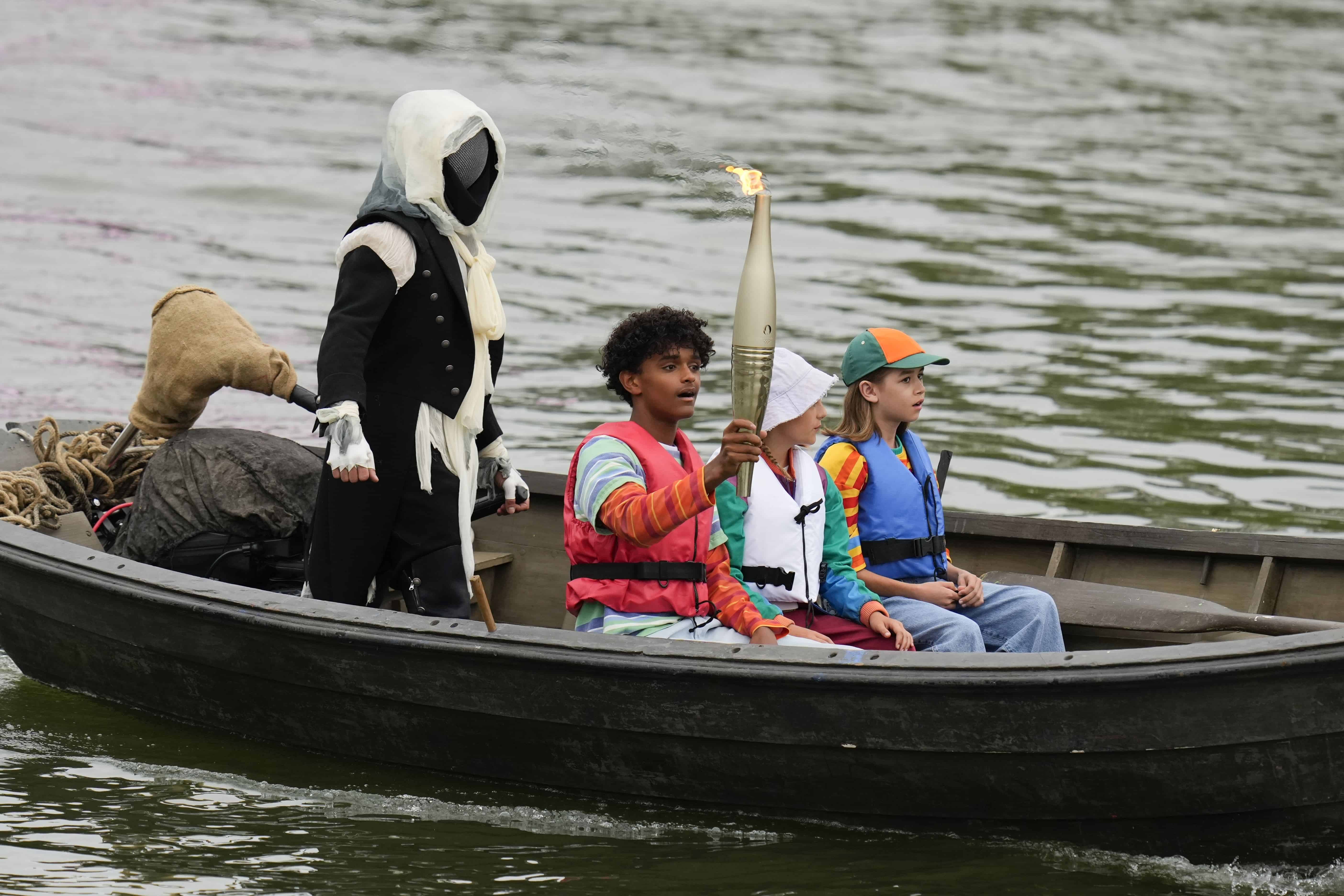 Se lleva una antorcha por el río Sena en París, Francia, durante la ceremonia de apertura de los Juegos Olímpicos de Verano de 2024, el viernes 26 de julio de 2024.