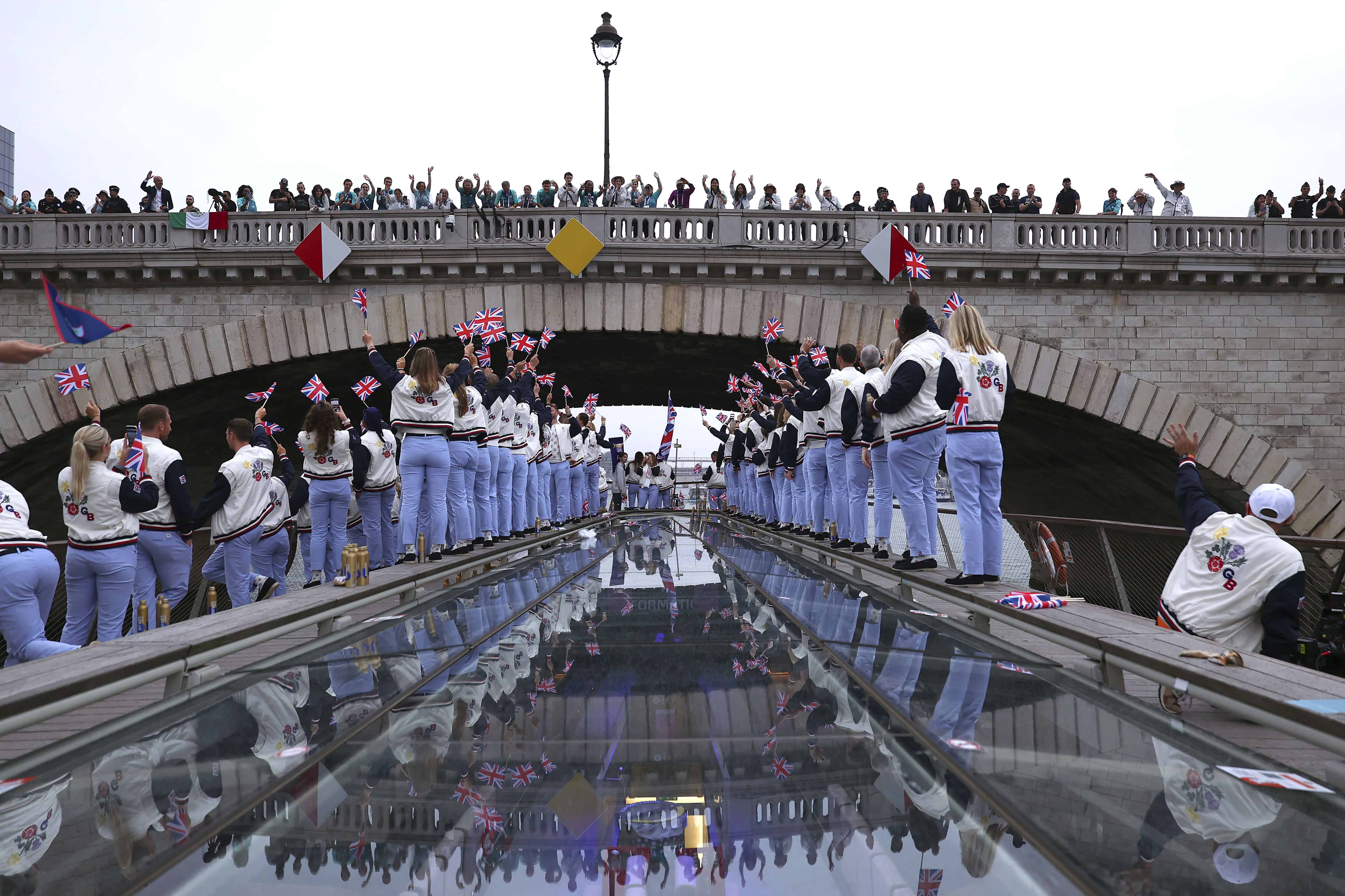 Los espectadores aplauden mientras los atletas de Gran Bretaña pasan bajo un puente a lo largo del río Sena durante la ceremonia de apertura de los Juegos Olímpicos de Verano de 2024 en París, Francia, el viernes 26 de julio de 2024.