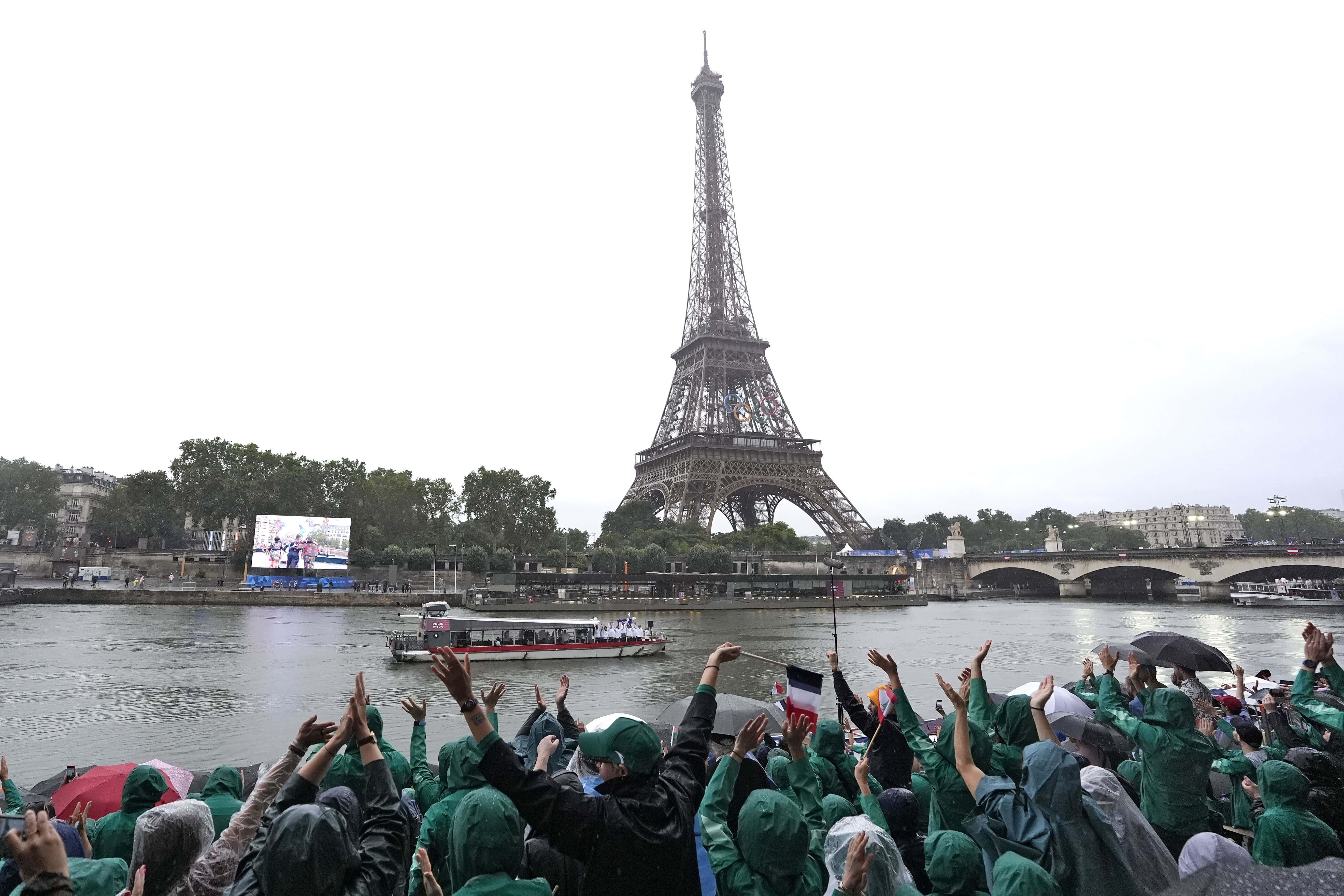 Un barco que transporta al Equipo Olímpico de Refugiados pasa mientras navegan por el río Sena mientras los espectadores saludan en París, Francia, durante la ceremonia de apertura de los Juegos Olímpicos de Verano de 2024, el viernes 26 de julio de 2024.