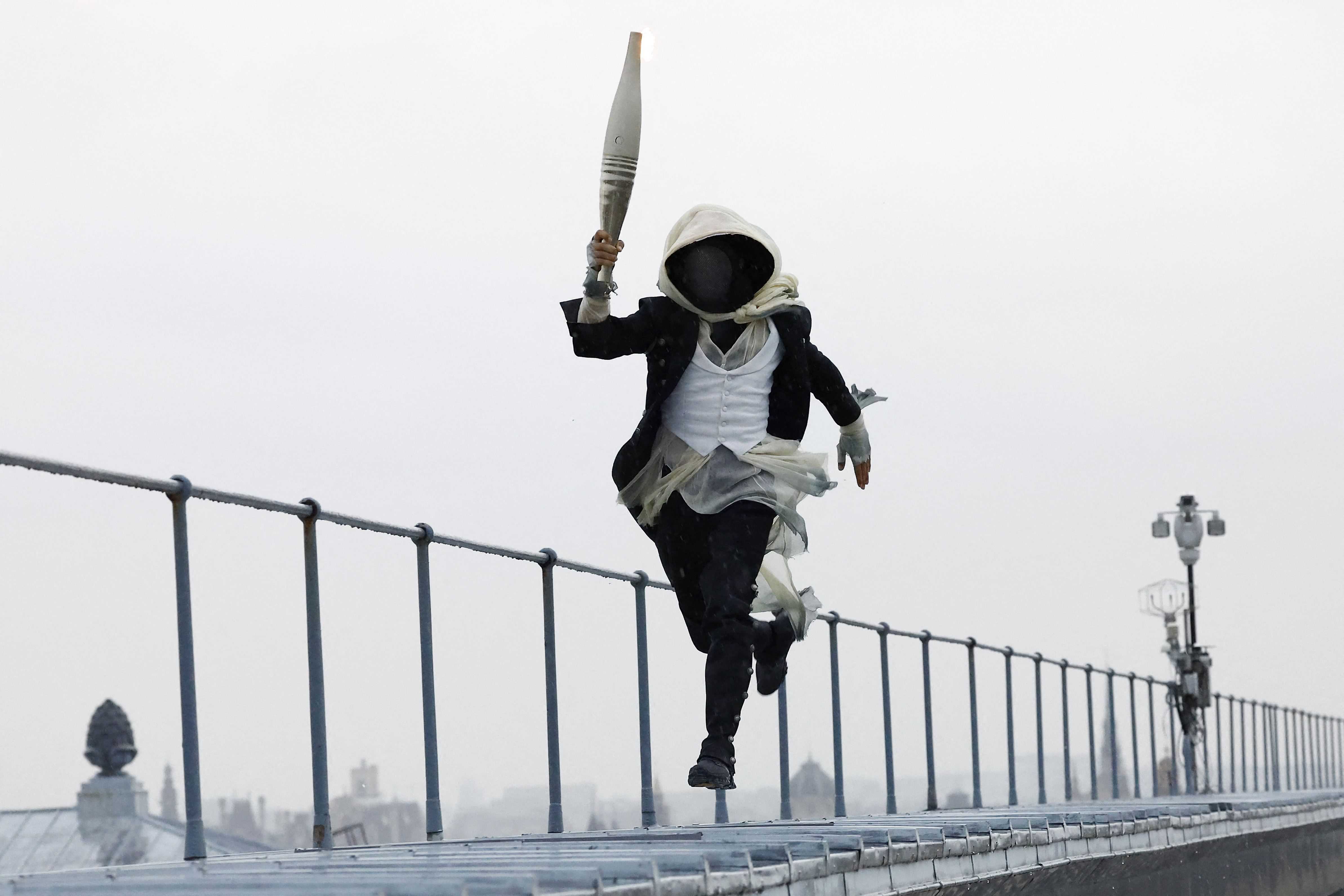 Un portador de la antorcha corre sobre el Museo de Orsay, en París, Francia, durante la ceremonia de apertura de los Juegos Olímpicos de Verano de 2024, el viernes 26 de julio de 2024.