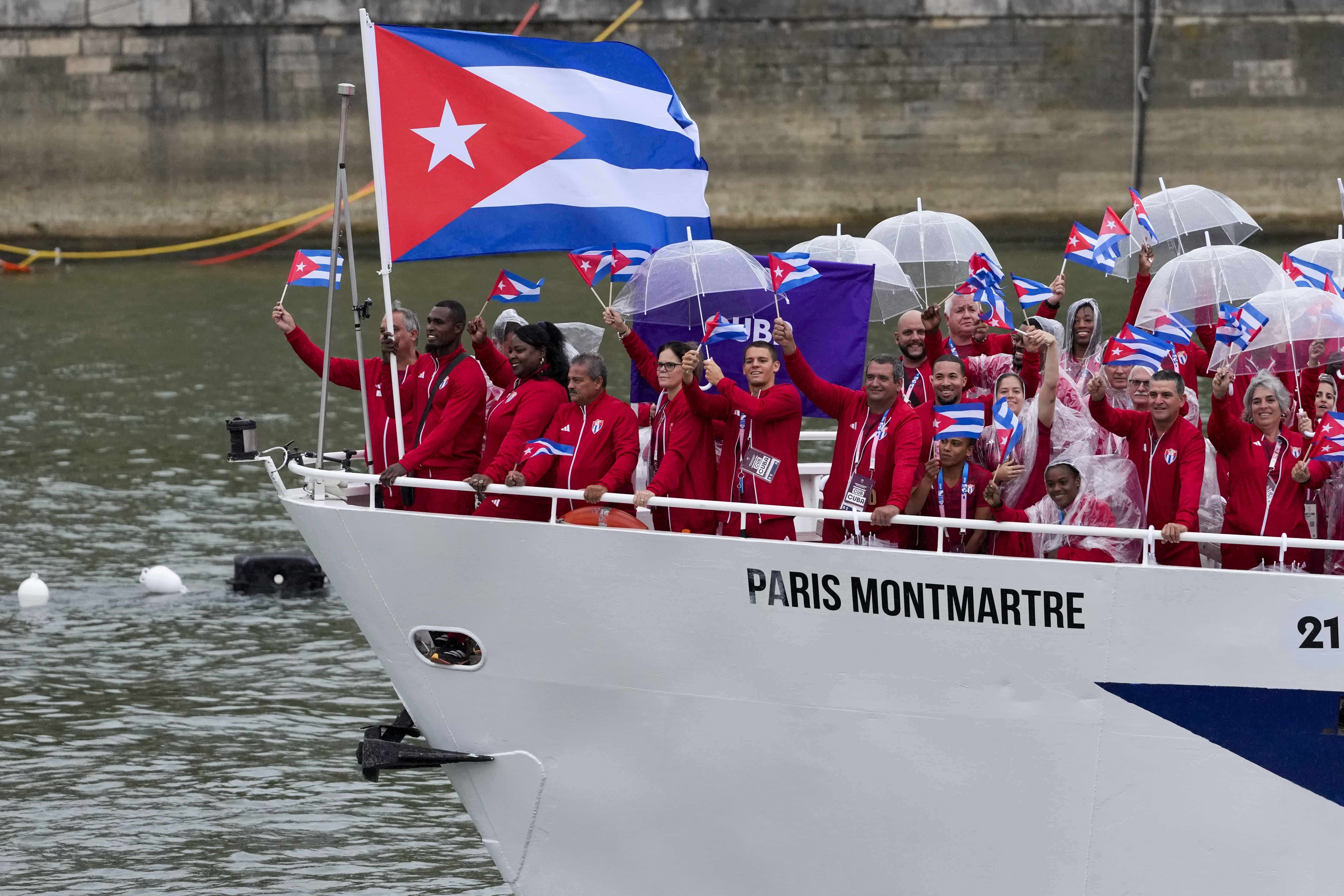 Los cubanos Julio César La Cruz Peraza e Idalys Ortiz viajan en un barco con compañeros de equipo por el río Sena en París, Francia, durante la ceremonia de apertura de los Juegos Olímpicos de Verano de 2024, el viernes 26 de julio de 2024.