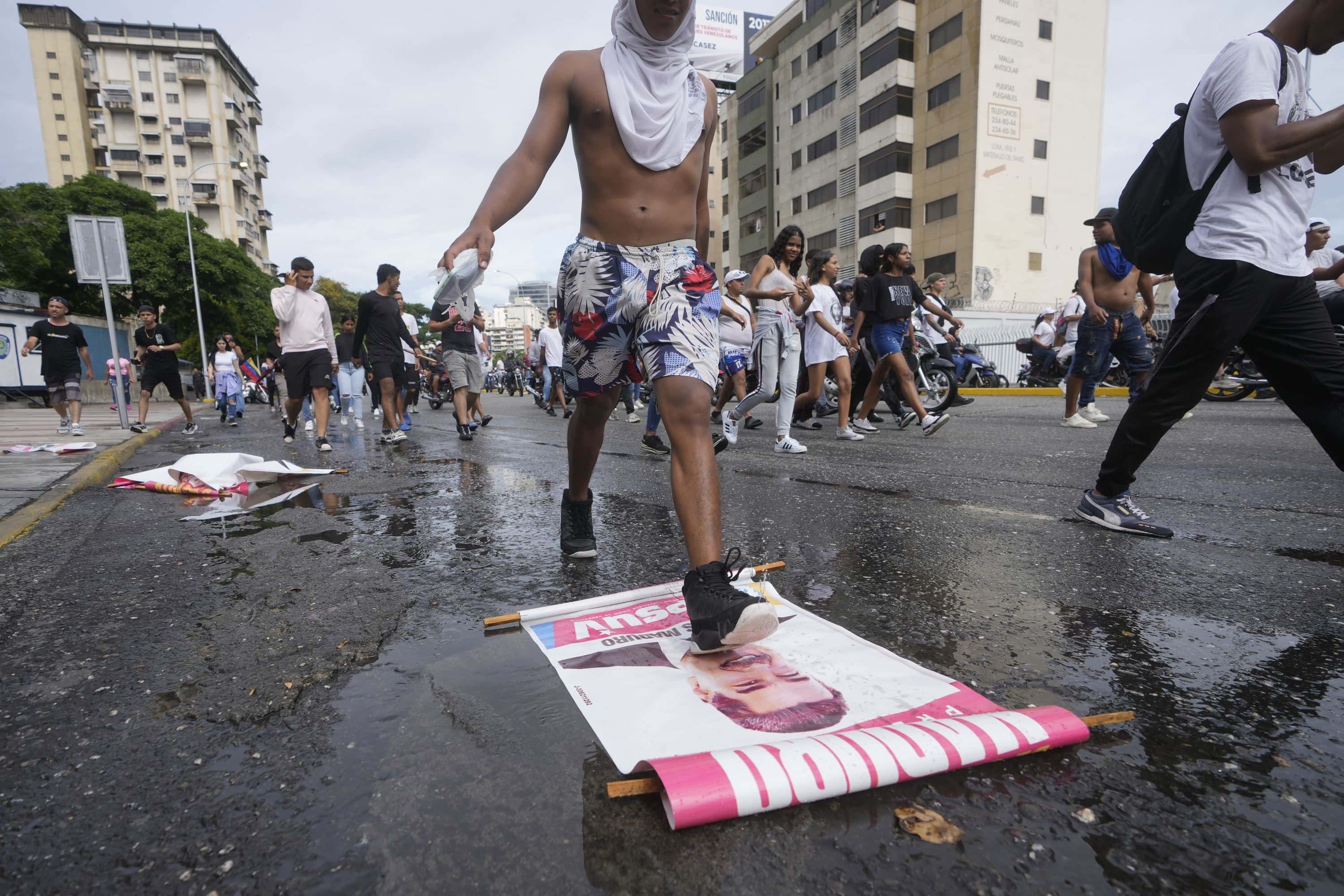 Un manifestante pisa un cartel de campaña del presidente Nicolás Maduro durante una marcha contra su declaración ganadora de las elecciones presidenciales, el día después de la votación en Caracas, Venezuela, el lunes 29 de julio de 2024.