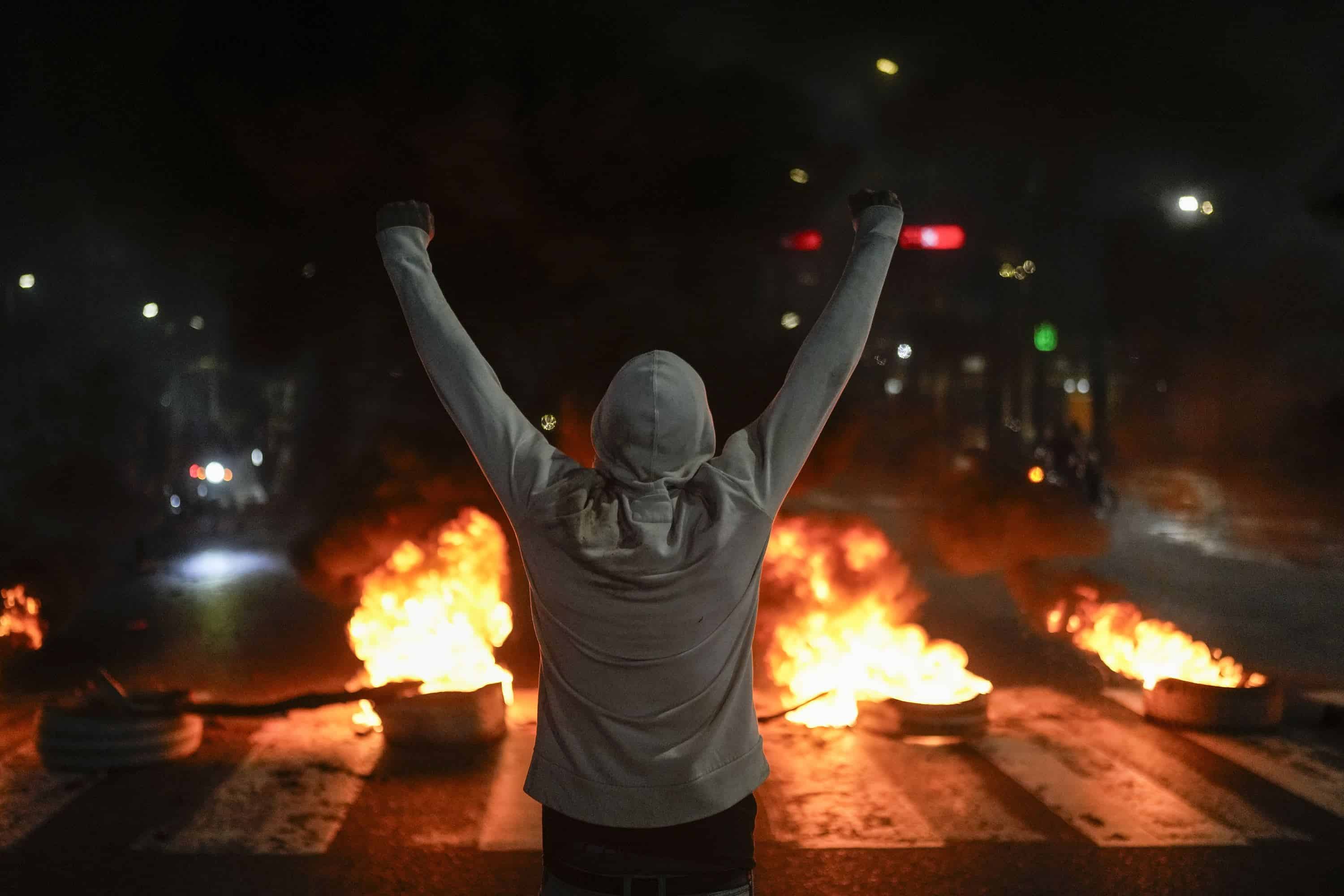 Un manifestante levanta los brazos frente a neumáticos en llamas en Caracas, Venezuela, el lunes 29 de julio de 2024, el día después de las elecciones presidenciales.