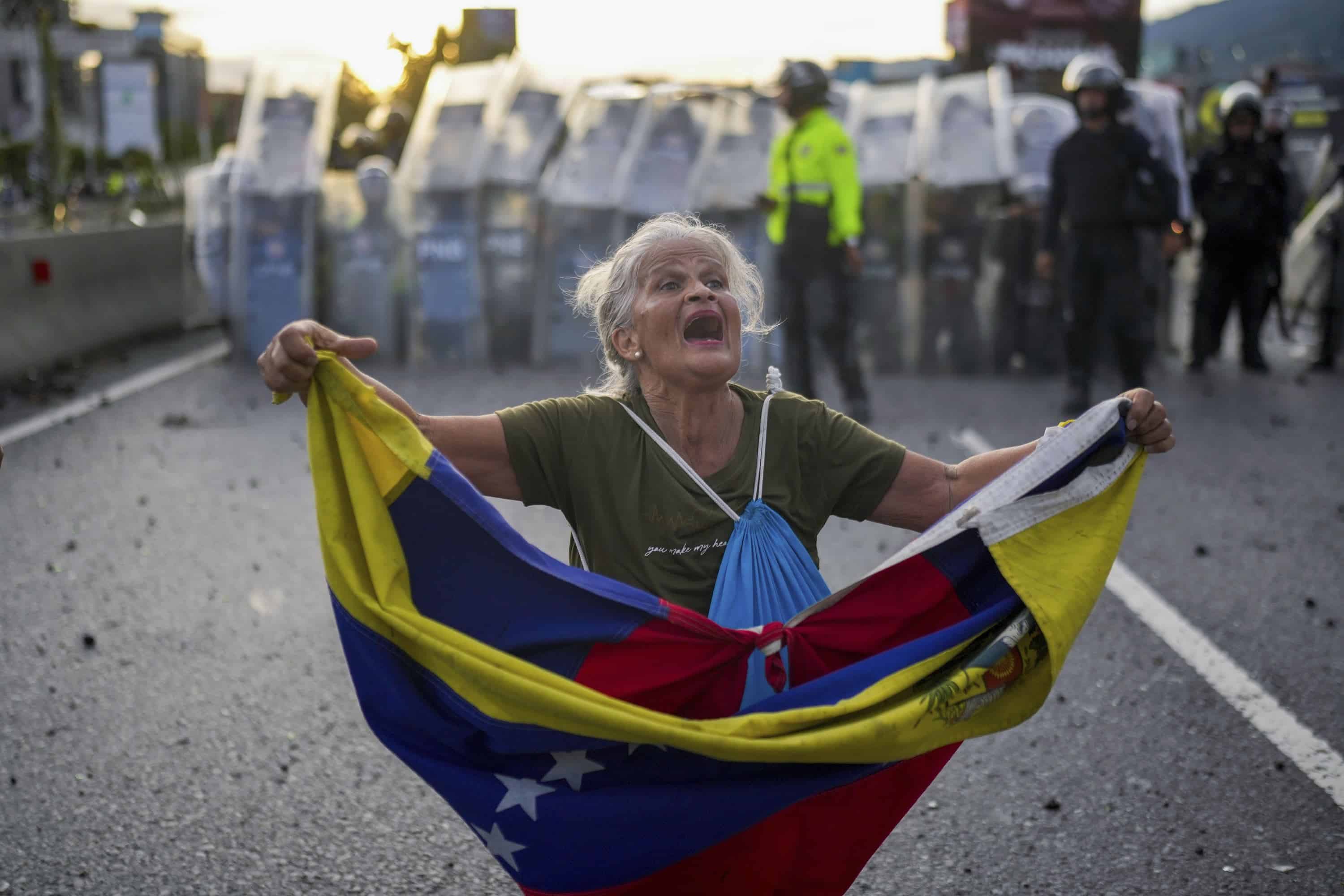 Consuelo Márquez con una bandera de Venezuela al frente de la policía que bloquea las manifestaciones contra los resultados de las elecciones que dieron por ganador a Nicolás Maduro, el día después de las votaciones en Caracas, Venezuela, el lunes 29 de julio de 2024.