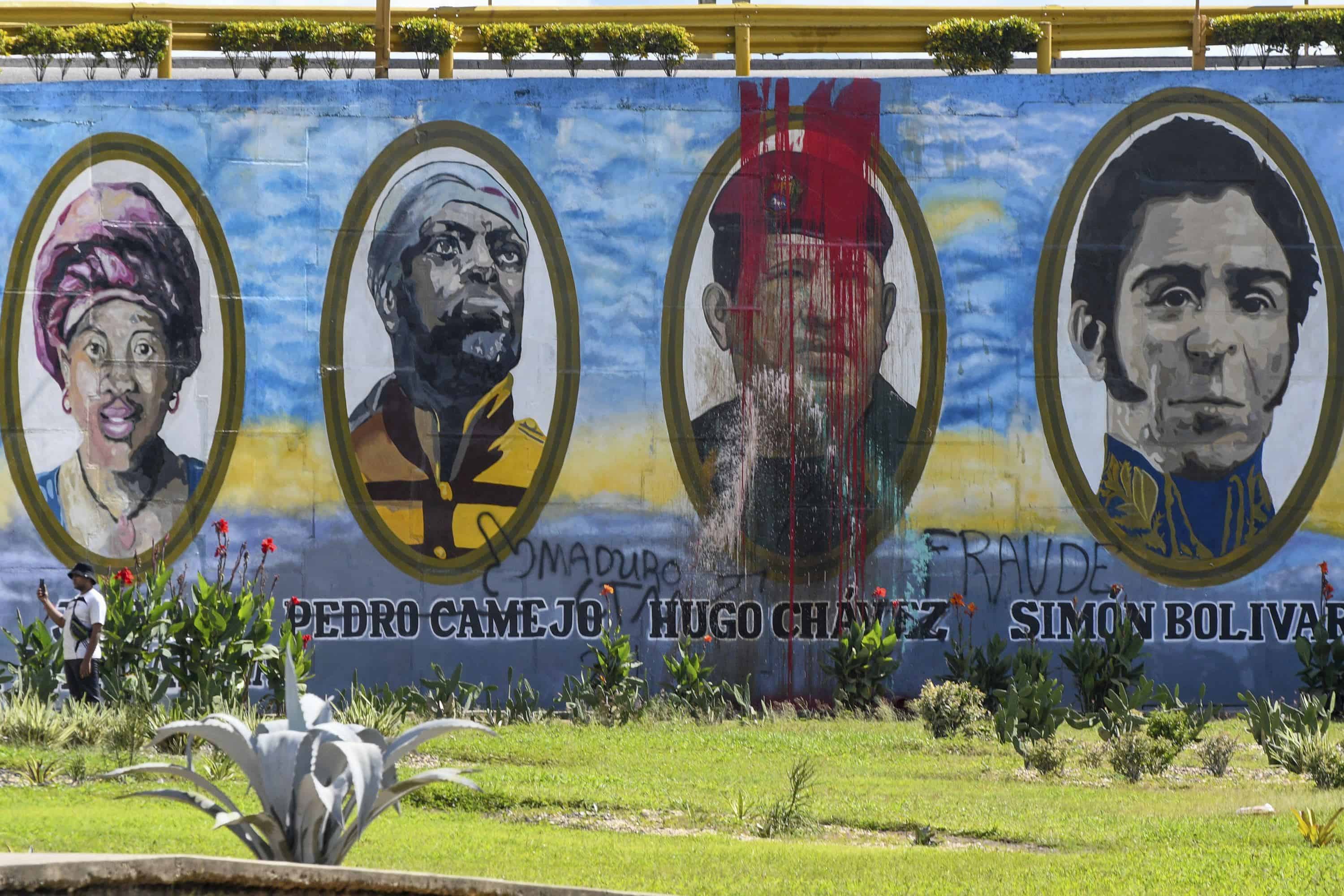 Un mural con pintura roja mancha el rostro del fallecido presidente venezolano Hugo Chávez, en el que aparece junto a héroes nacionales históricos, tras las protestas en contra de los resultados oficiales de las elecciones que declararon ganador al protegido de Chávez, el presidente Nicolás Maduro, en Valencia, Venezuela, el martes 30 de julio de 2024, dos días después de las elecciones.