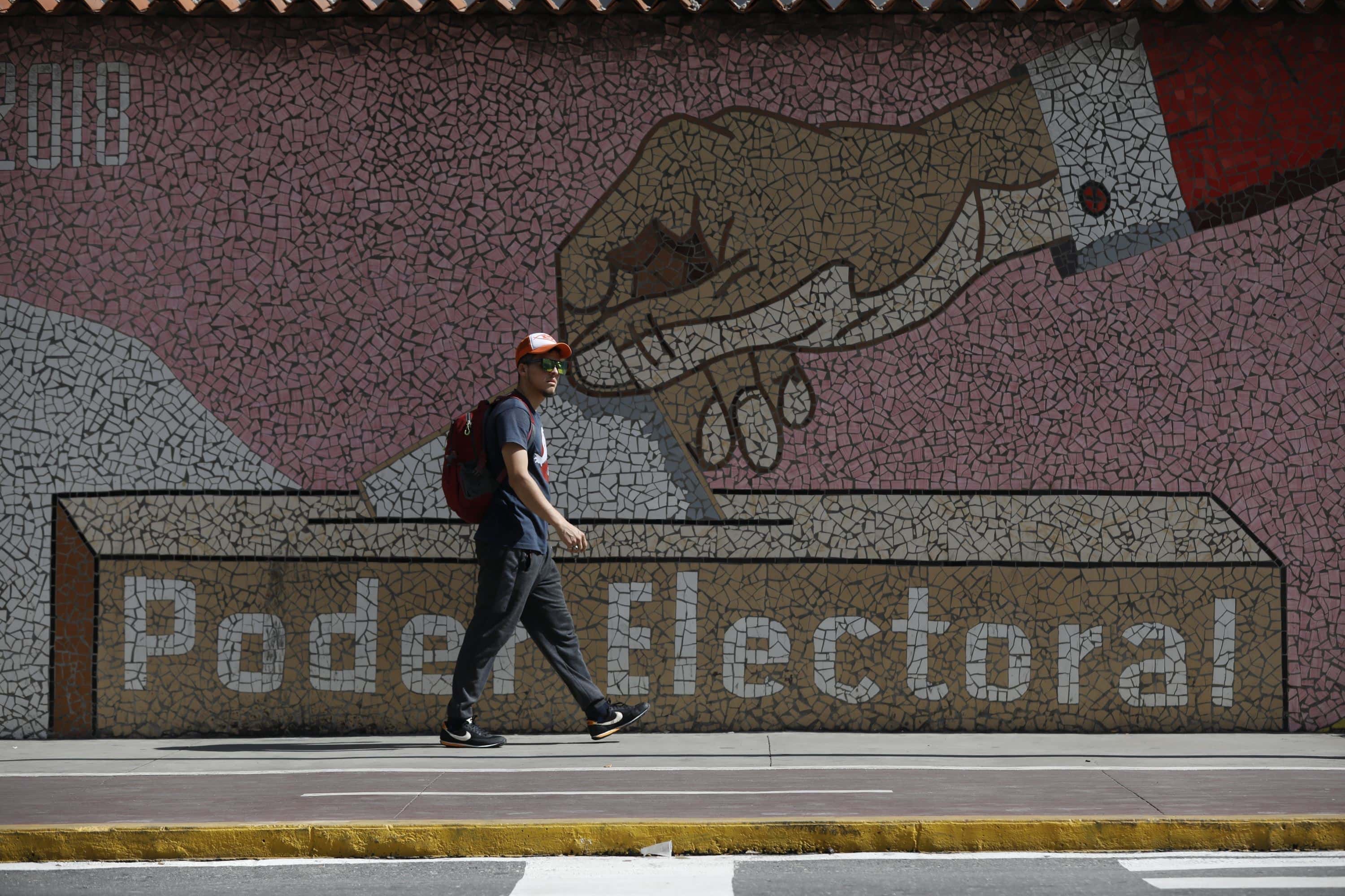 Un hombre camina junto a un mural que representa una urna, frente a la sede del Consejo Nacional Electoral en Caraca, Venezuela, el miércoles 31 de julio de 2024, tres días después de que el país enfrentara una controvertida elección presidencia.