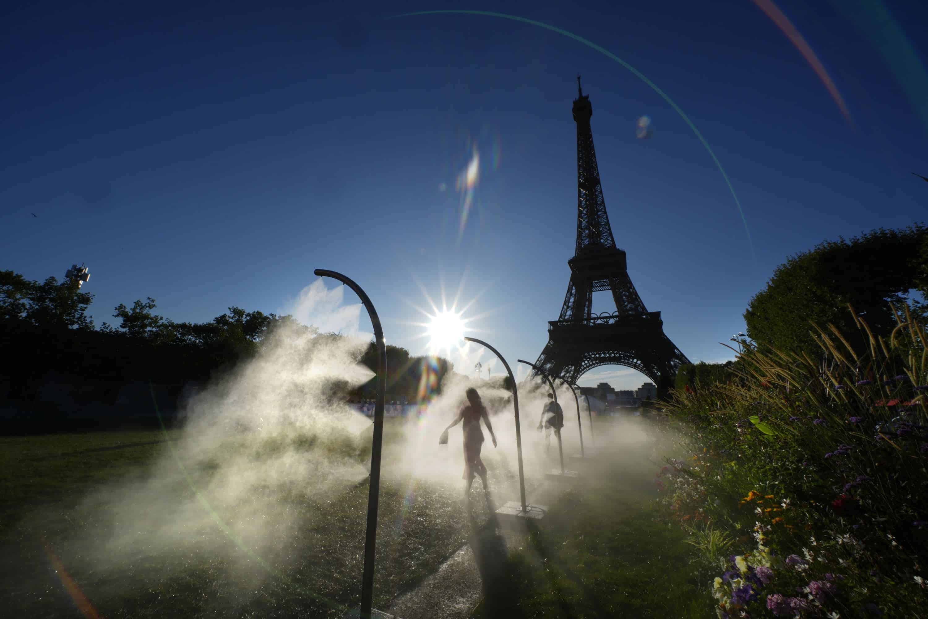 Un espectador camina a través de un rociador de agua de camino al estadio de la Torre Eiffel para ver un partido de voleibol de playa en los Juegos Olímpicos de Verano de 2024, el domingo 28 de julio de 2024, en París, Francia.