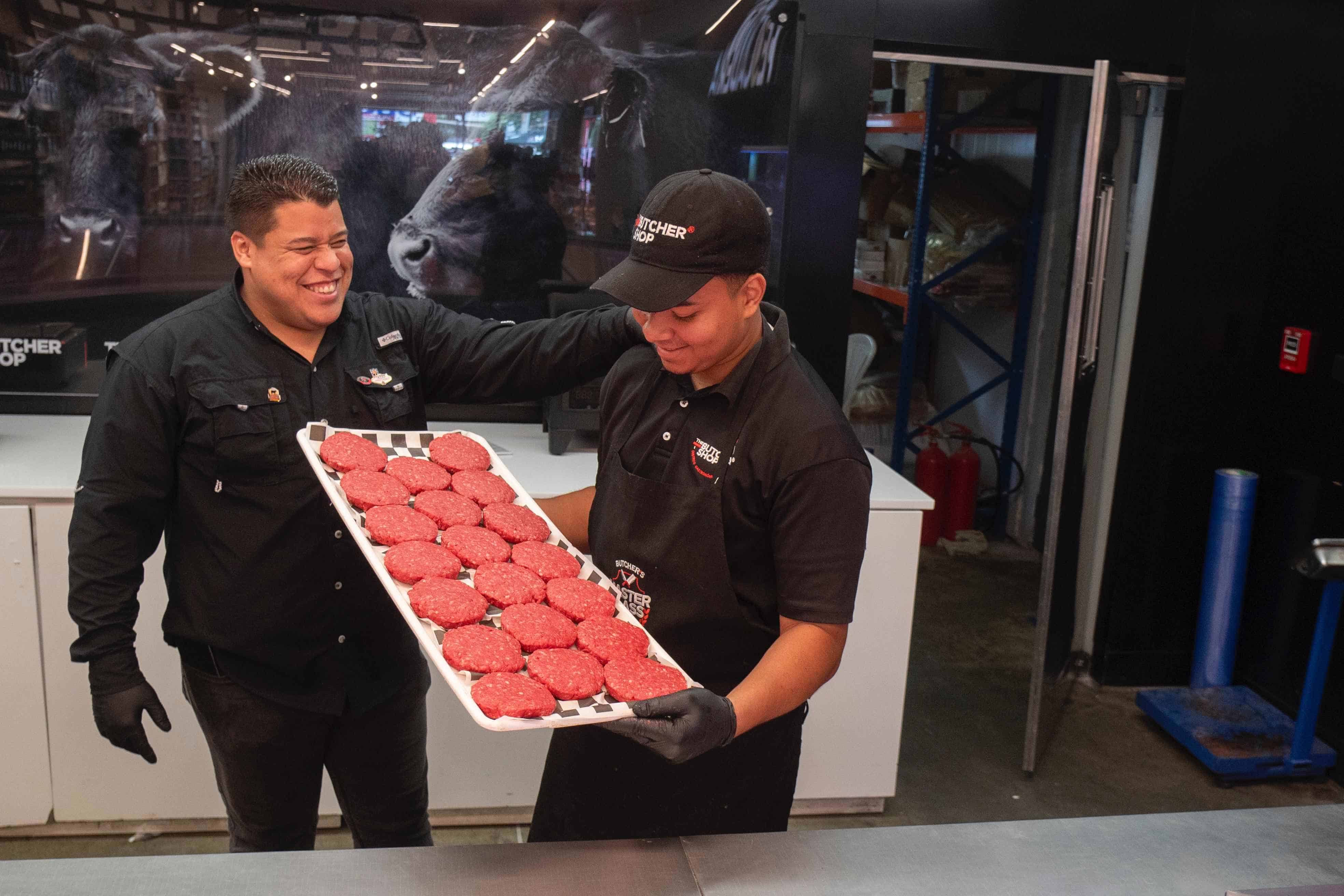 Dos empleados muestran la carne en venta.