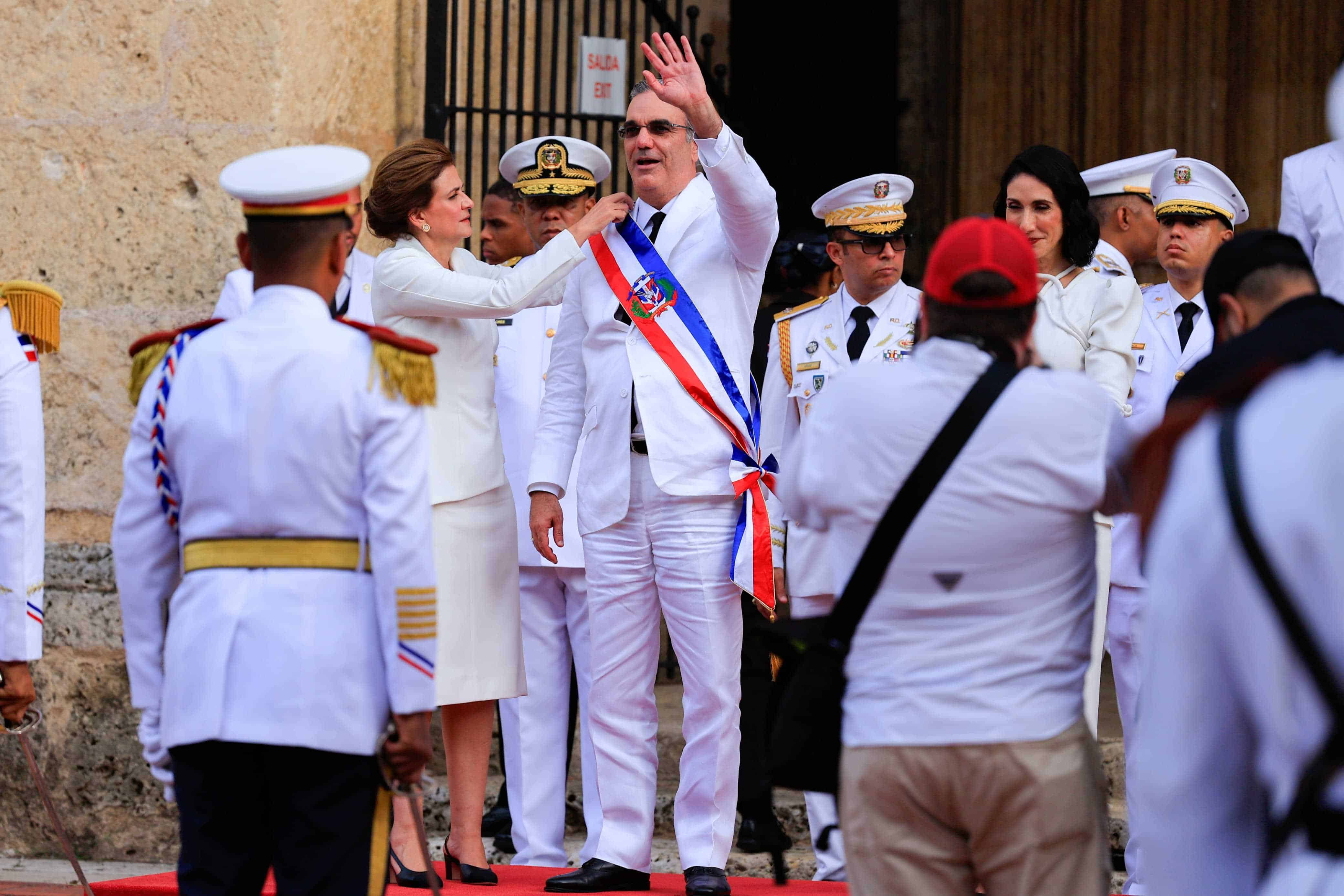 La vicepresidenta Raquel Peña le acomoda la banda presidencial a Luis Abinader.