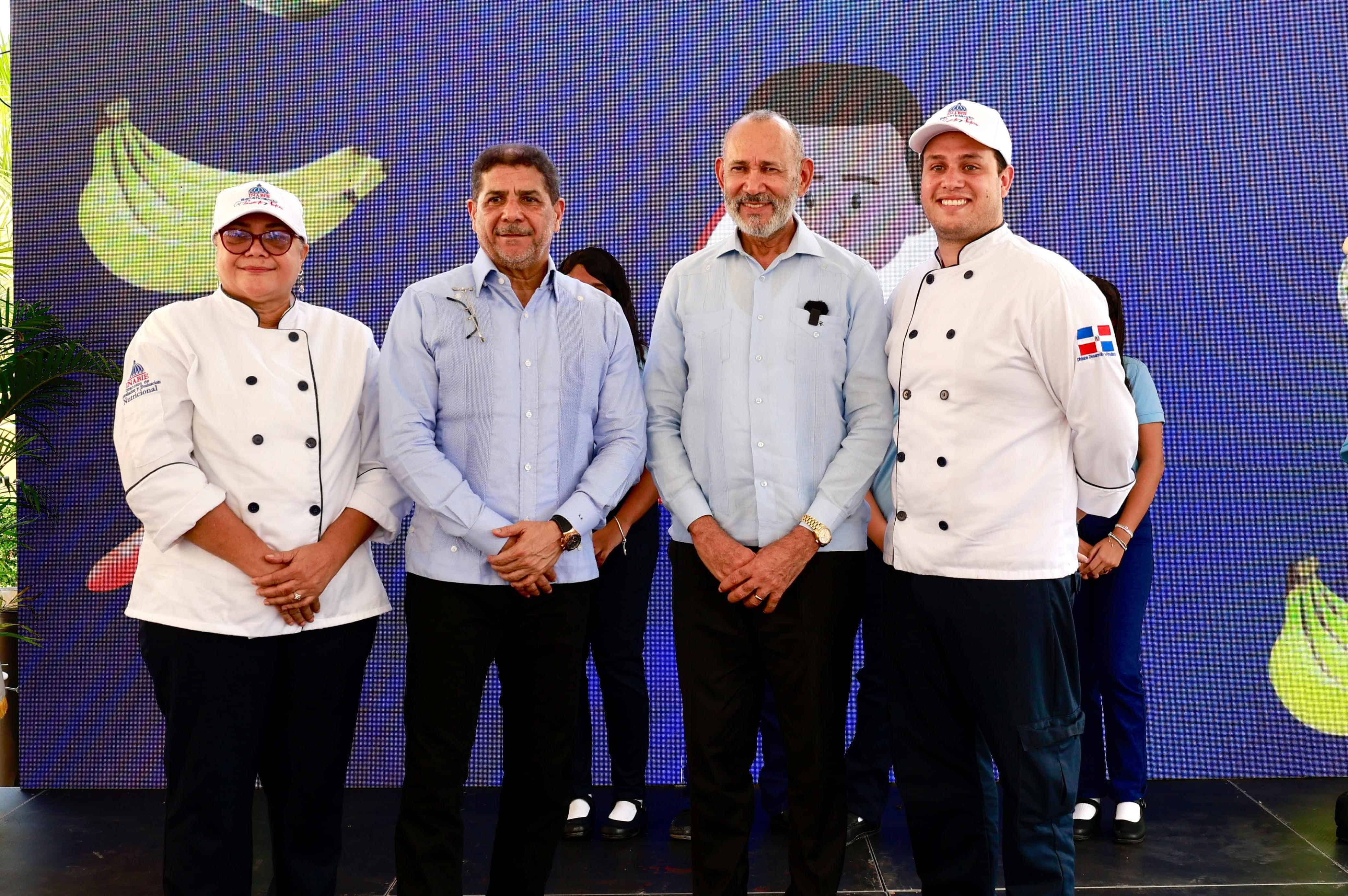 El ministro de Agricultura, Limber Cruz López, y el director ejecutivo del INABIE, Víctor Castro, junto posan con dos cocineros de escuelas.