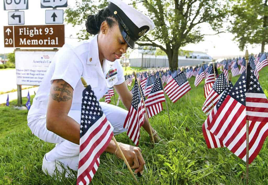 El suboficial jefe de la Marina de los EE. UU., Tyranae Murray, marinero del USS Somerset de Victorville, California, coloca una de las últimas 40 banderas, en honor a los pasajeros y la tripulación perdidos en el vuelo 93, en una exhibición ubicada en Harmon Street en el condado de Somerset, Pensilvania, el lunes. , 9 de septiembre de 2024.