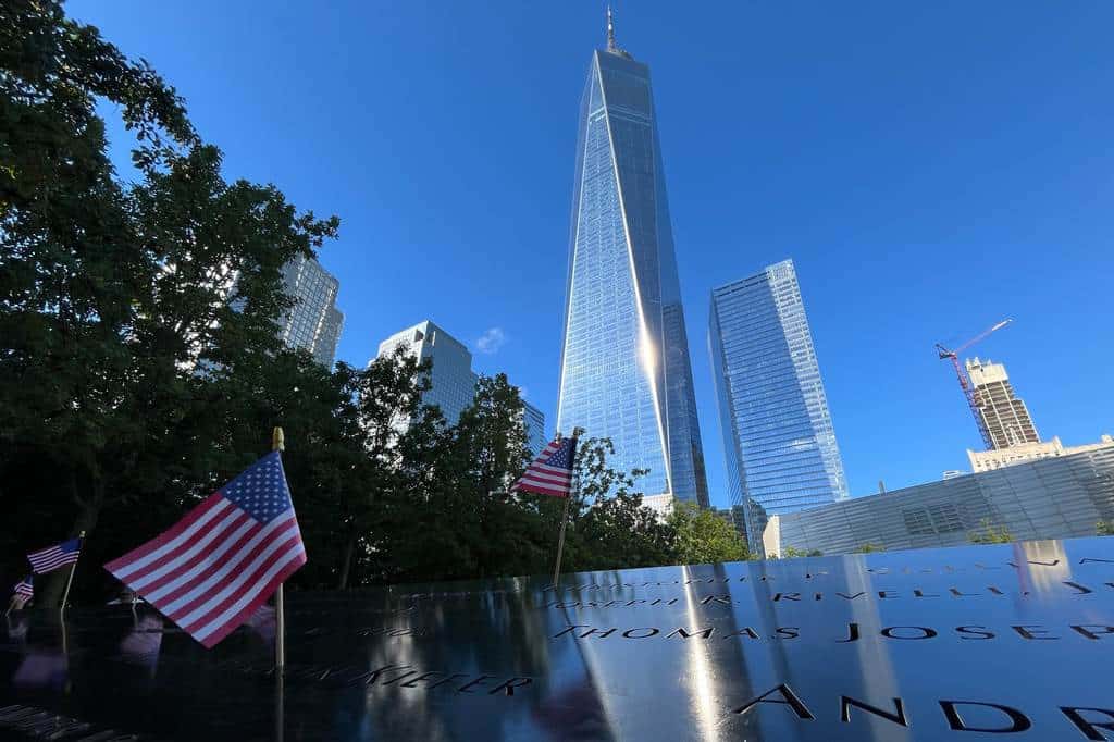 Se colocan banderas junto a los nombres de los muertos durante los ataques del 11 de septiembre de 2001 en los estanques reflectantes del Museo y Memorial Nacional del 11 de Septiembre, el martes 10 de septiembre de 2024, en Nueva York. Al fondo se eleva el One World Trade Center.