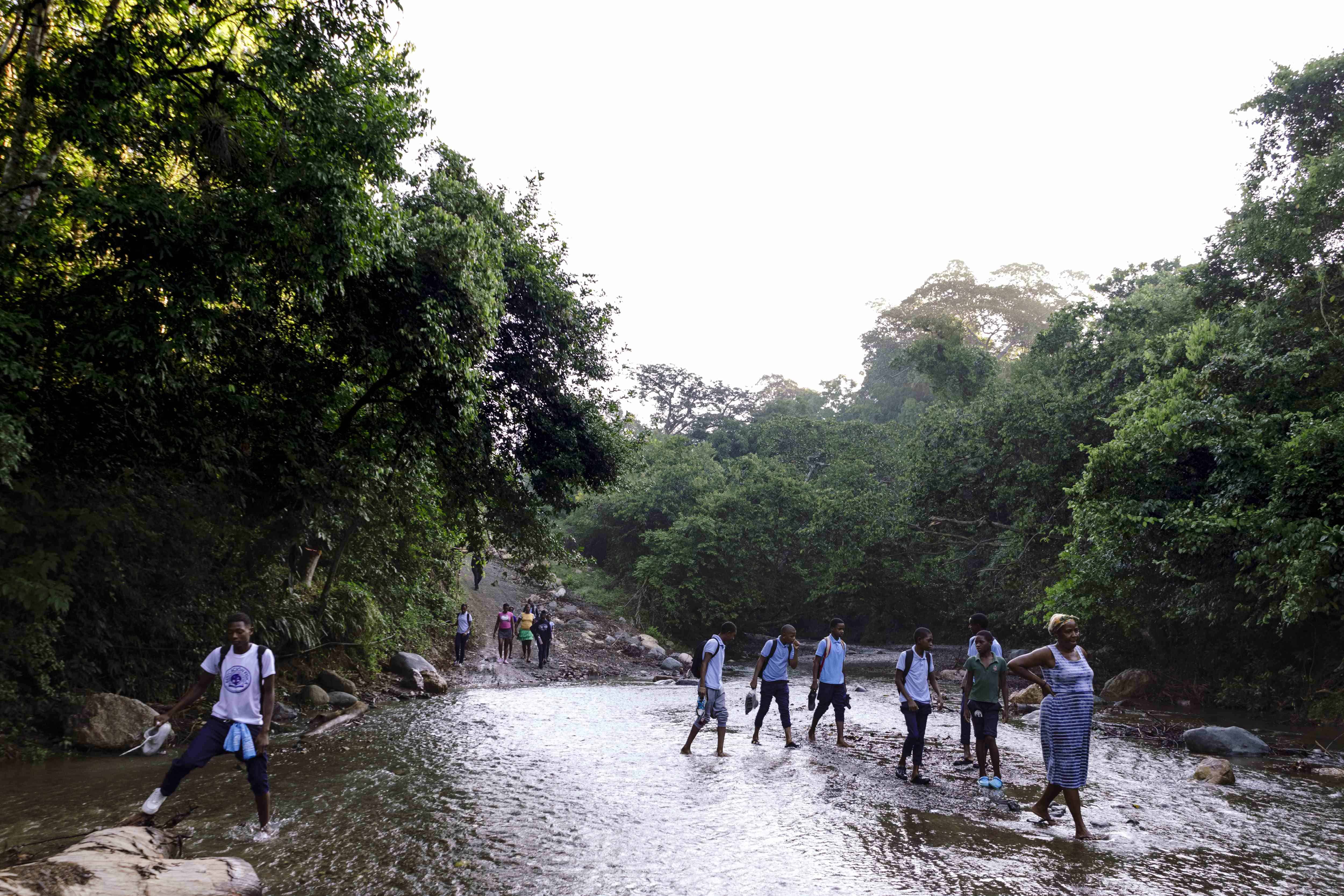 Estudiantes cruzando el río para ir a la escuela.<br>