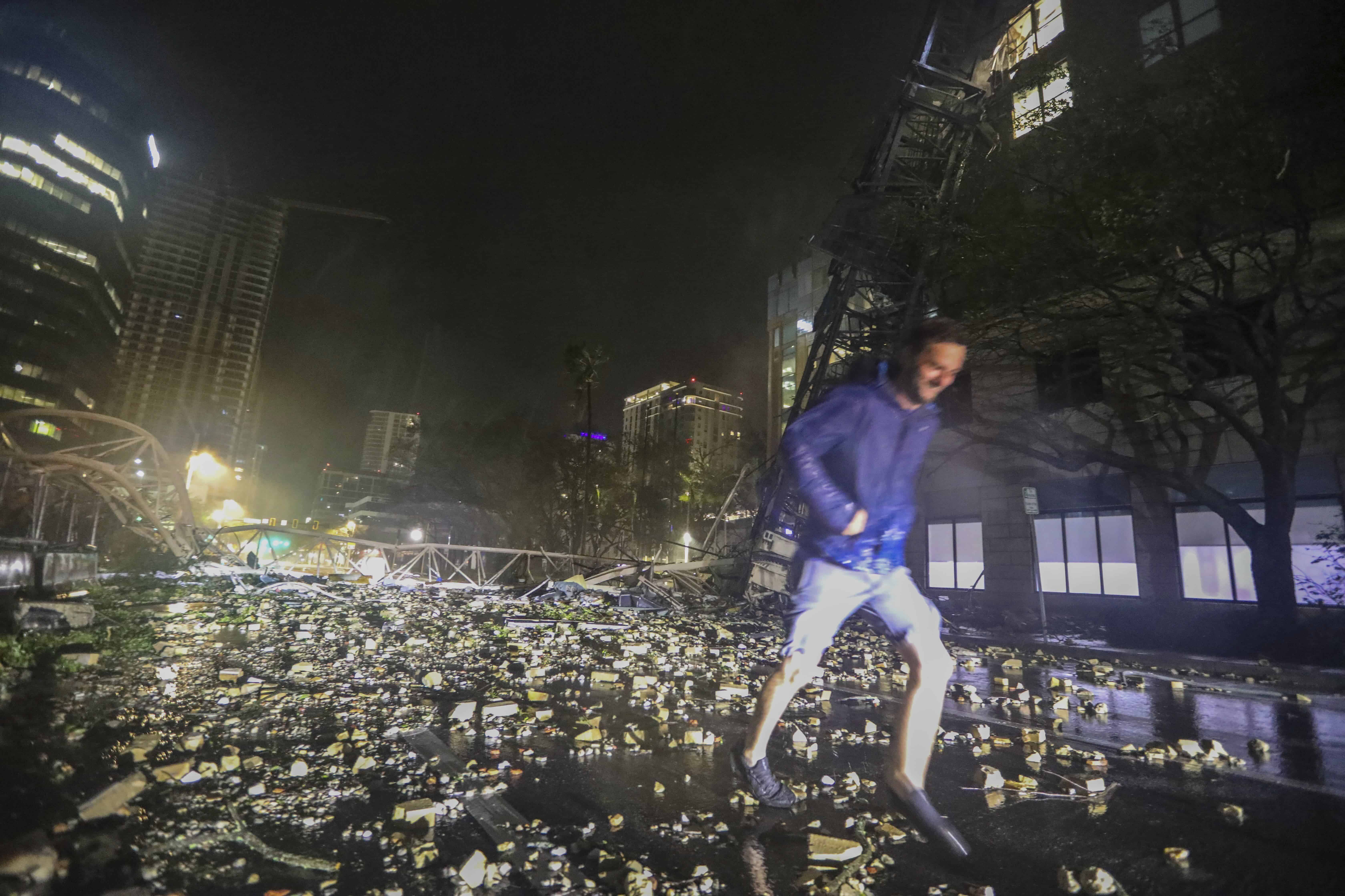 Joe Lindquist, de 32 años, de San Petersburgo, camina sobre ladrillos cerca de una grúa caída a lo largo de 1st Avenue South cerca de las oficinas del Tampa Bay Times en San Petersburgo, Florida, el jueves 10 de octubre de 2024, mientras los fuertes vientos del huracán Milton arrasaban el área.