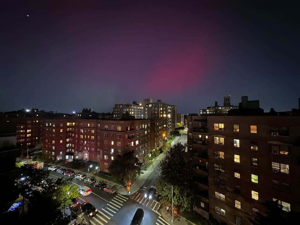 Una aurora boreal, también conocida como aurora boreal, brilla en el cielo nocturno sobre edificios de apartamentos en el distrito de Queens de Nueva York, el jueves 10 de octubre de 2024.