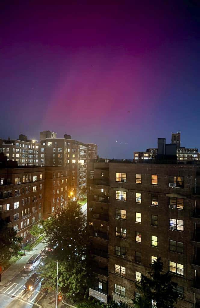 Una aurora boreal, también conocida como aurora boreal, brilla en el cielo nocturno sobre edificios de apartamentos en el distrito de Queens de Nueva York, el jueves 10 de octubre de 2024.