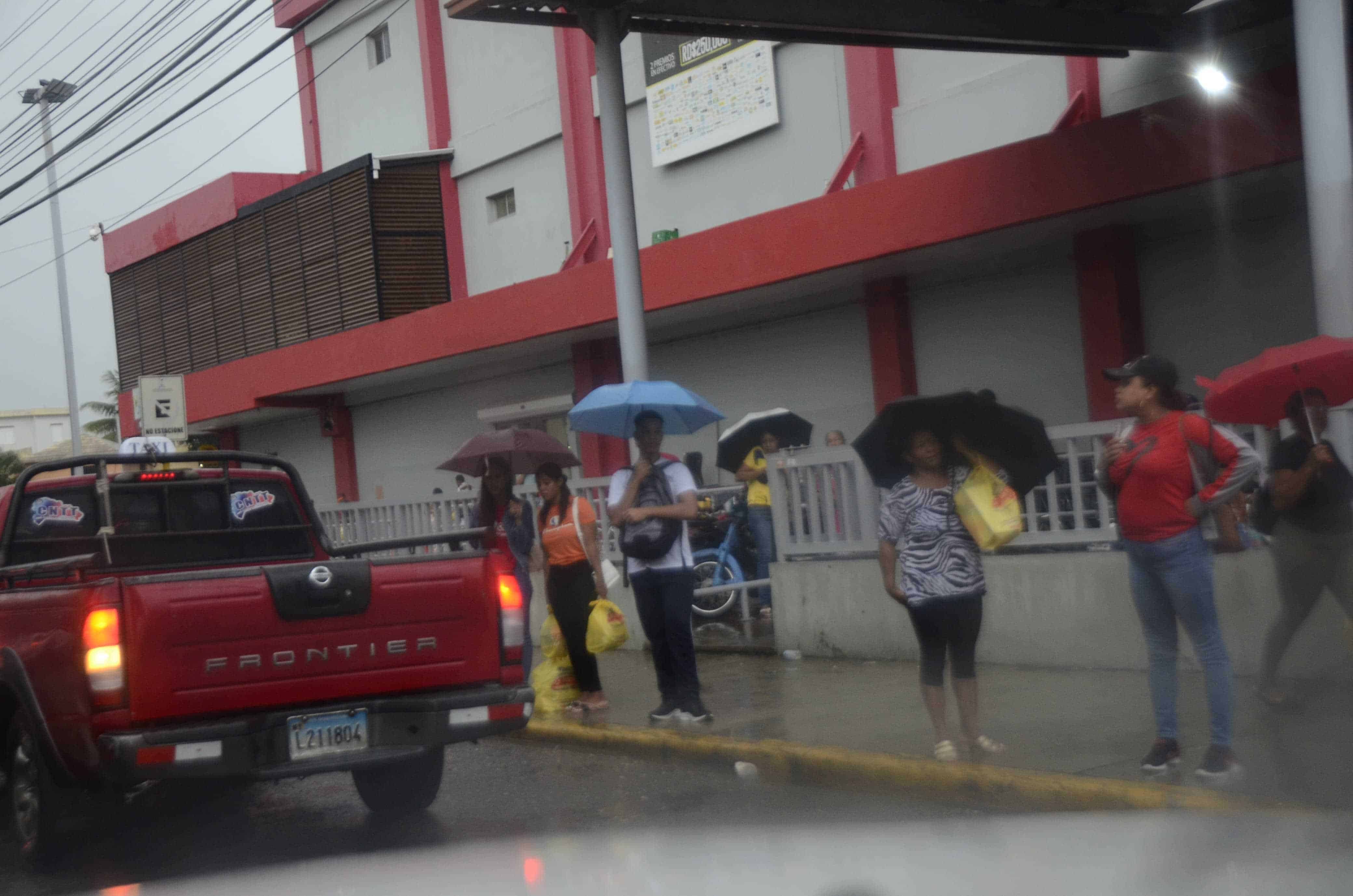 Personas esperan transporte en medio de la lluvia en Santiago.