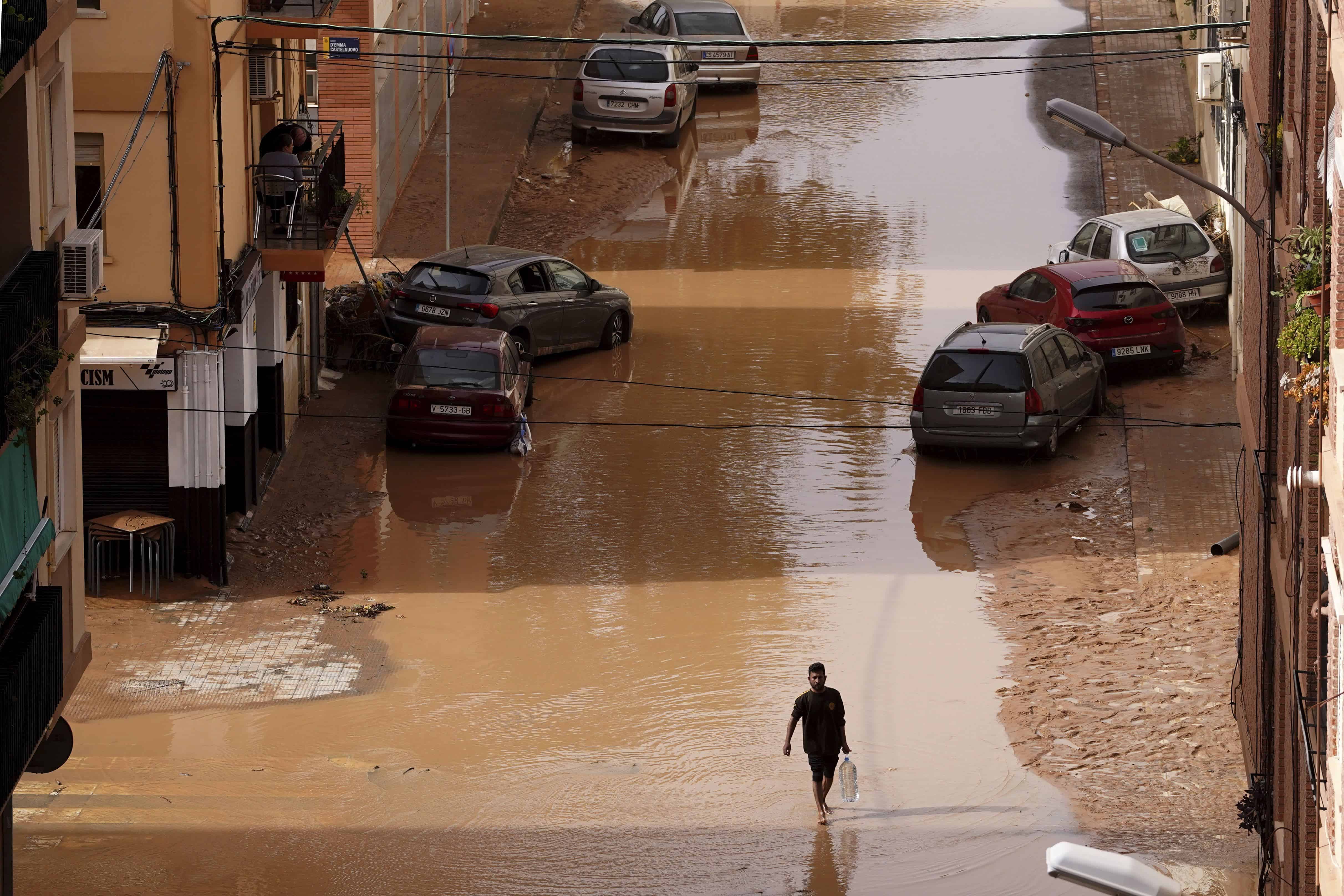 A man carrying water walks through flooded streets in Valencia, Spain, Wednesday, Oct. 30, 2024.