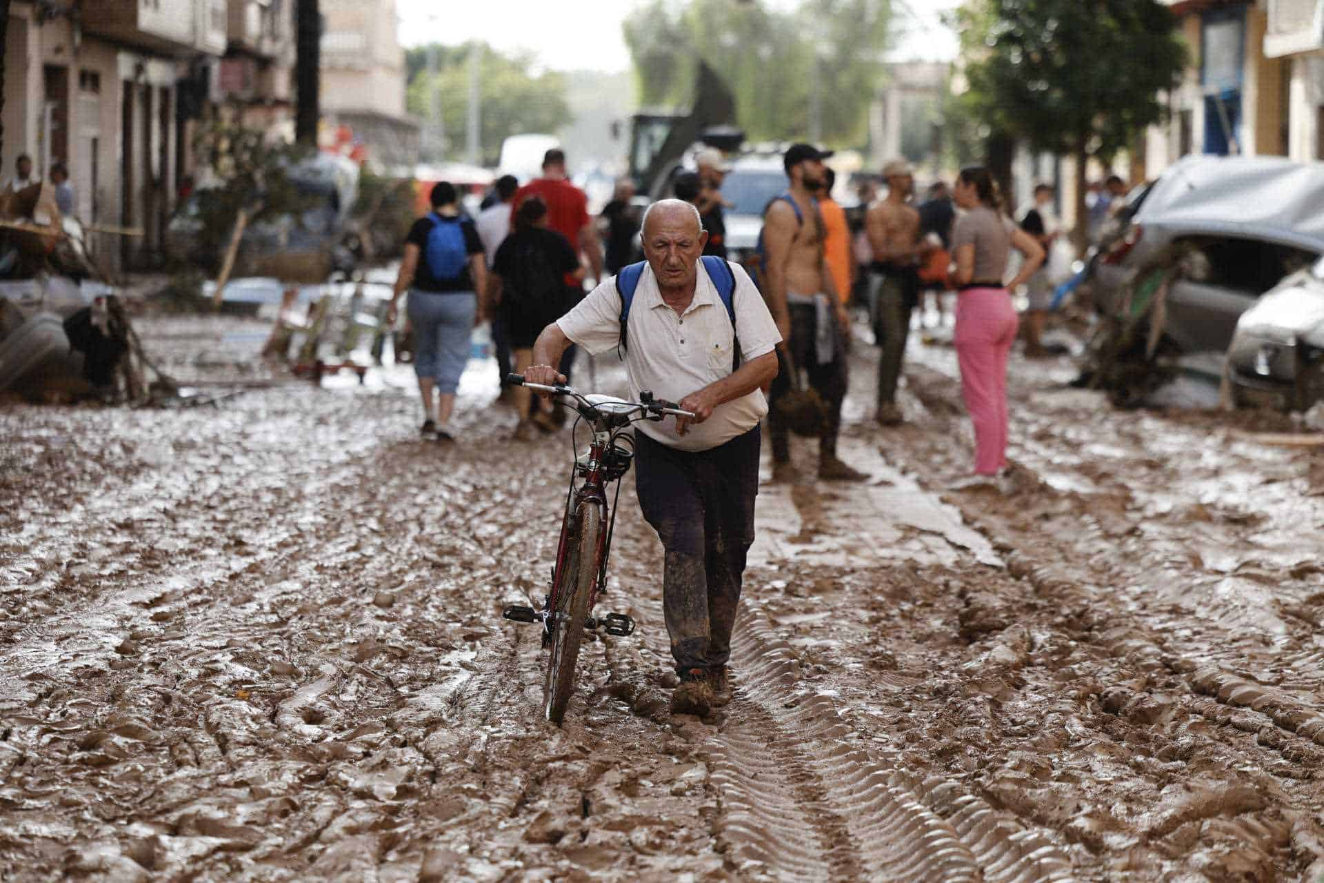 Hombre andando con su bicicleta en una zona afectada por la DANA. 