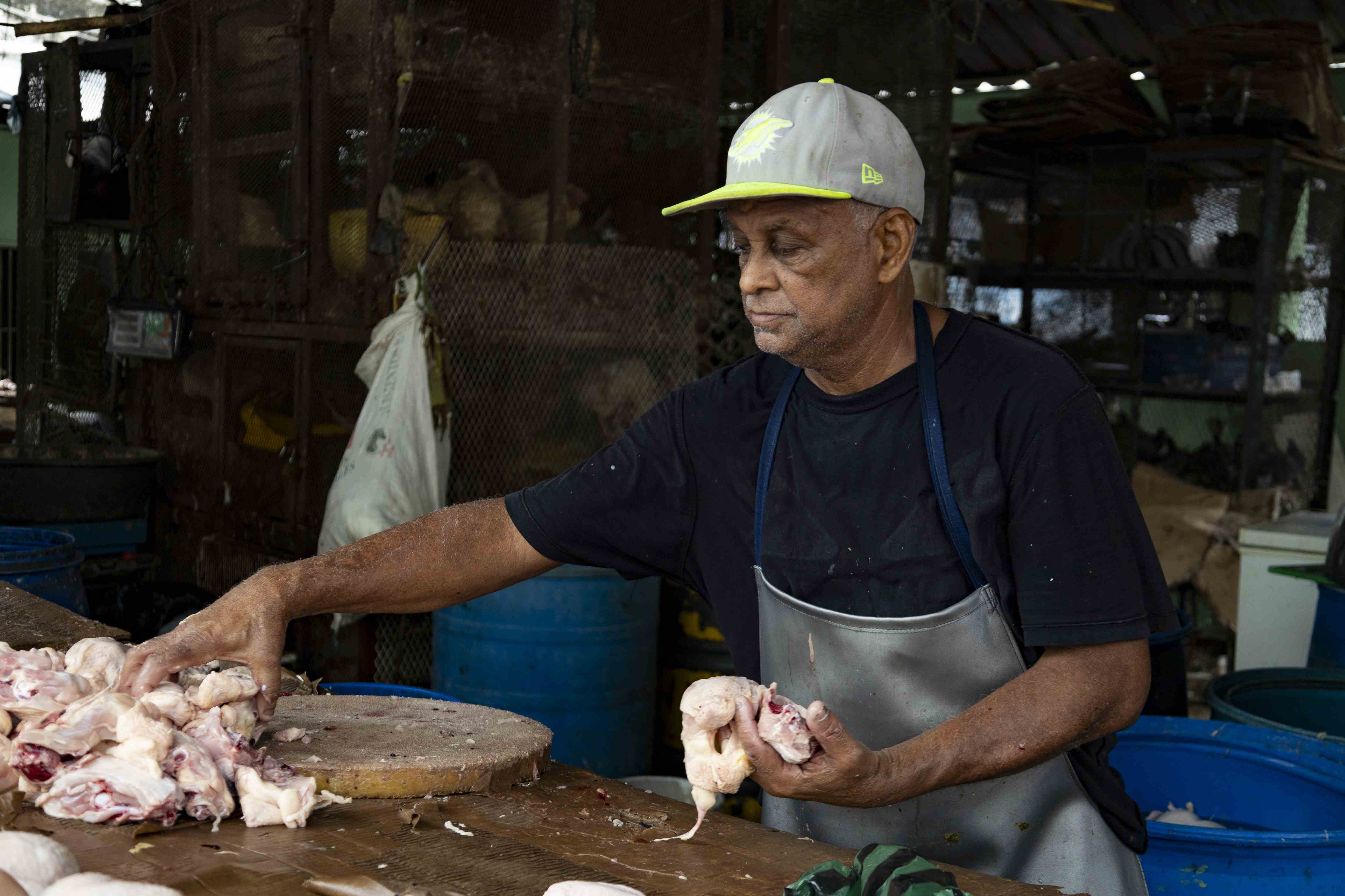 Francis toma en su mano unas piezas de pollo para servir a un cliente en el mercado modelo.