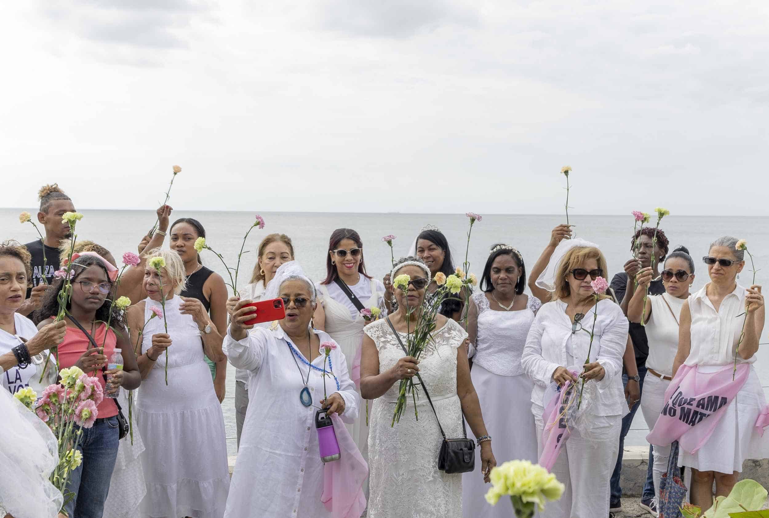 Manifestantes alzan flores para lanzarlas al mar en memoria de las víctimas de feminicidio.