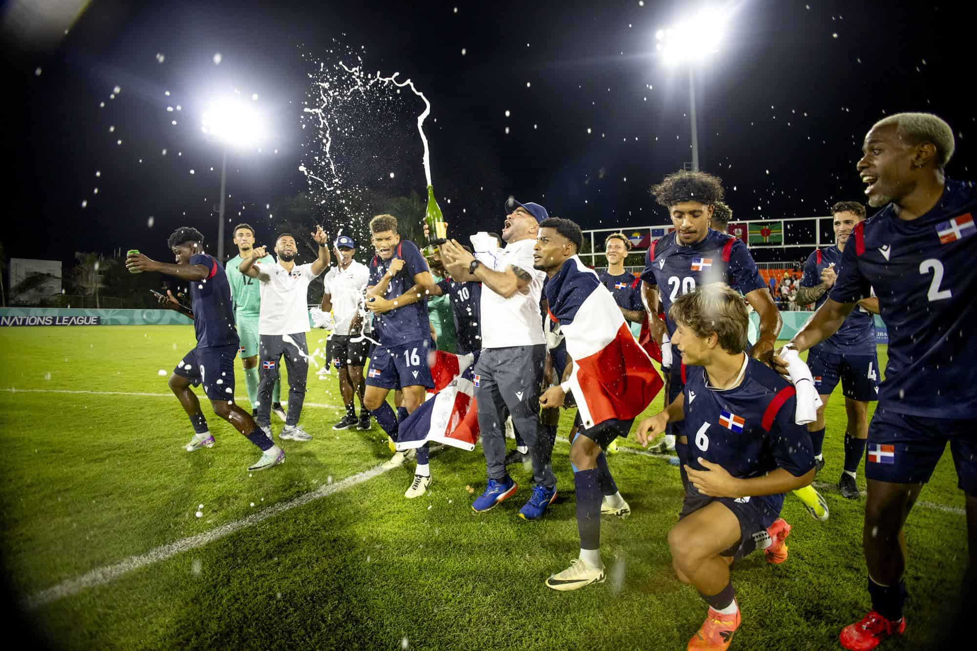 Con espumante, bandera y mucha alegría los integrantes de la selección dominicana de fútbol celebran tras dominar categóricamente su grupo en la Concacaf Nations League.