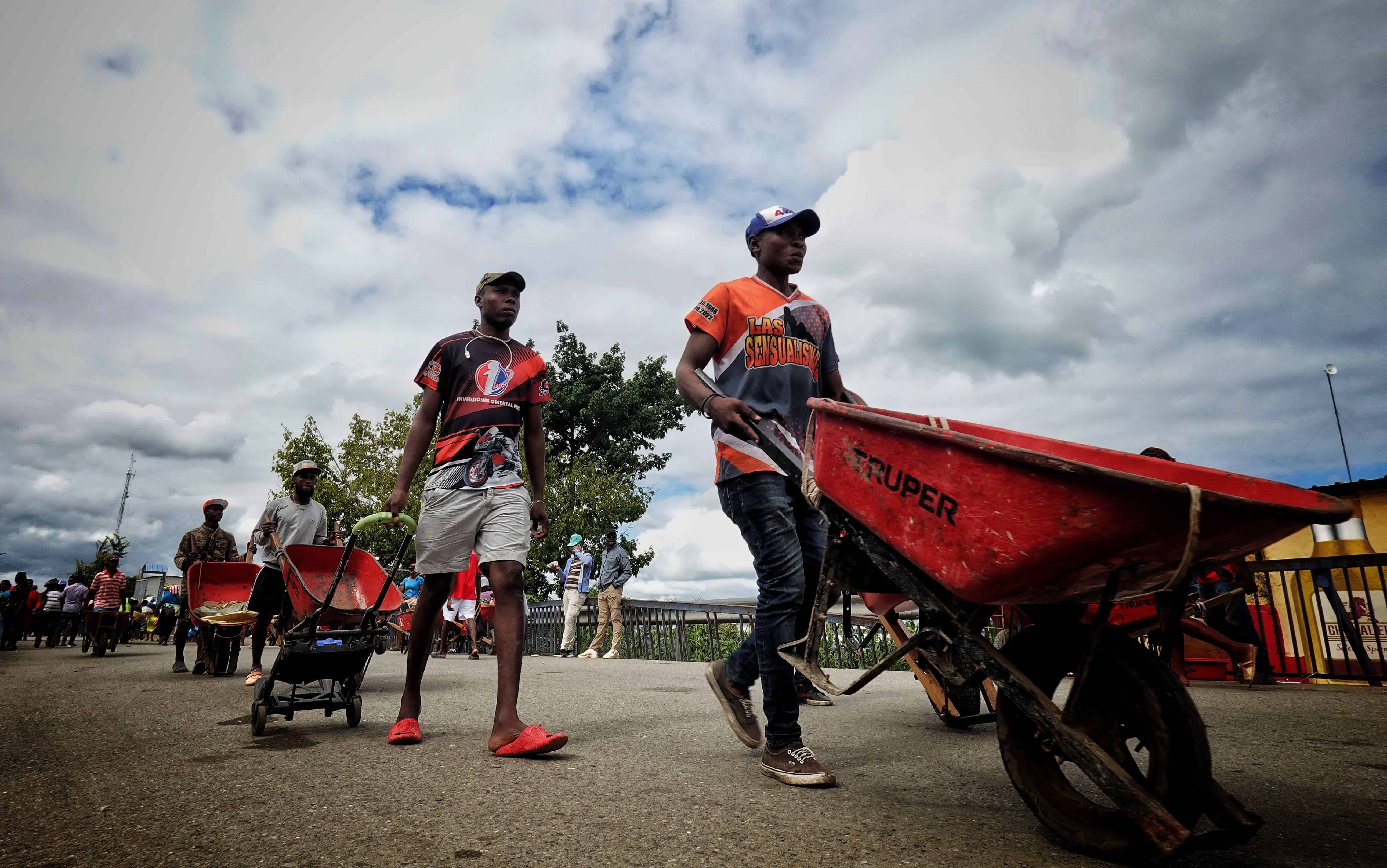 Haitianos, con carretillas, entran a República Dominicana para comprar en el mercado.