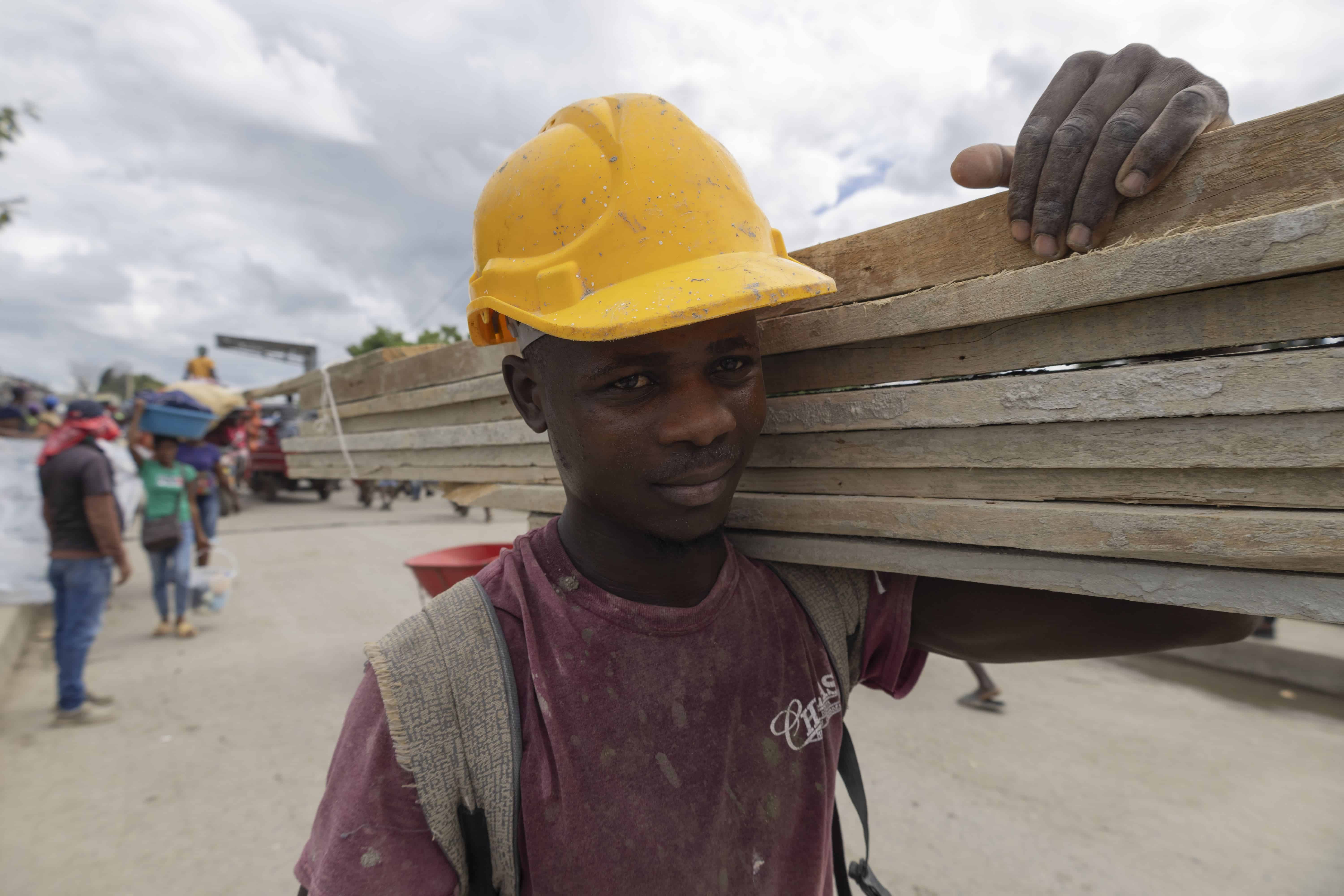 Un haitiano carga trozos de madera en el mercado.