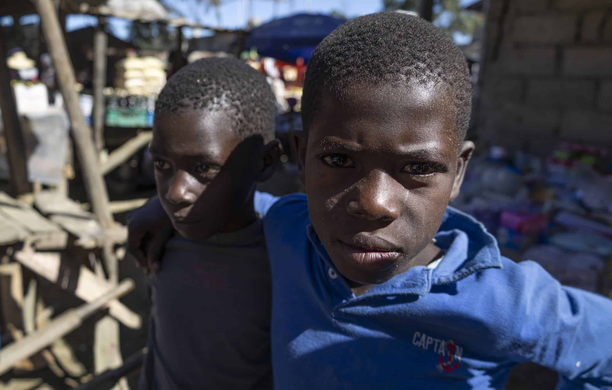 Dos niños haitianos, bajo el sol, en las entrañas del mercado.