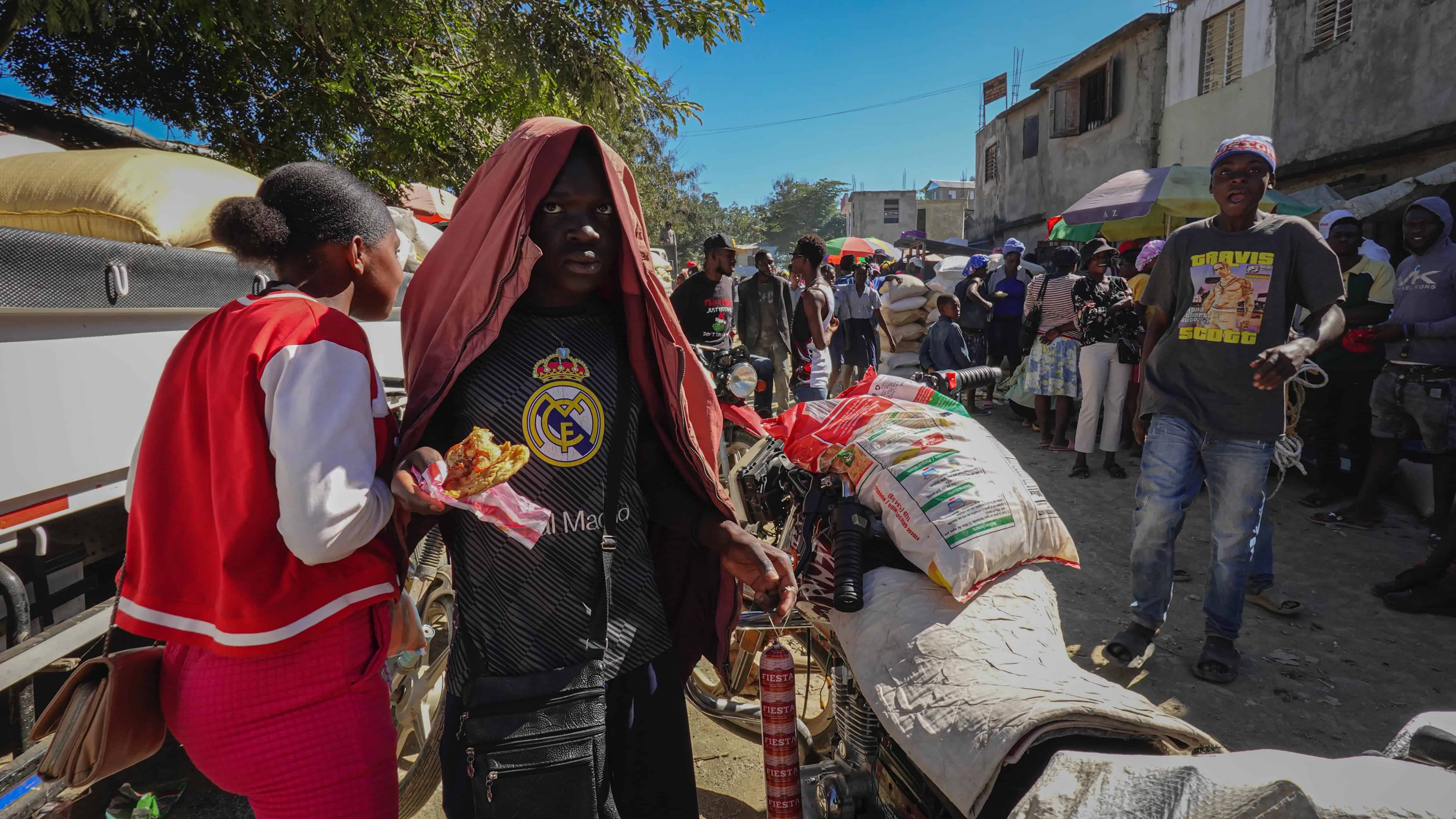 Un joven haitiano, con la camiseta del Madrid, comiendo.