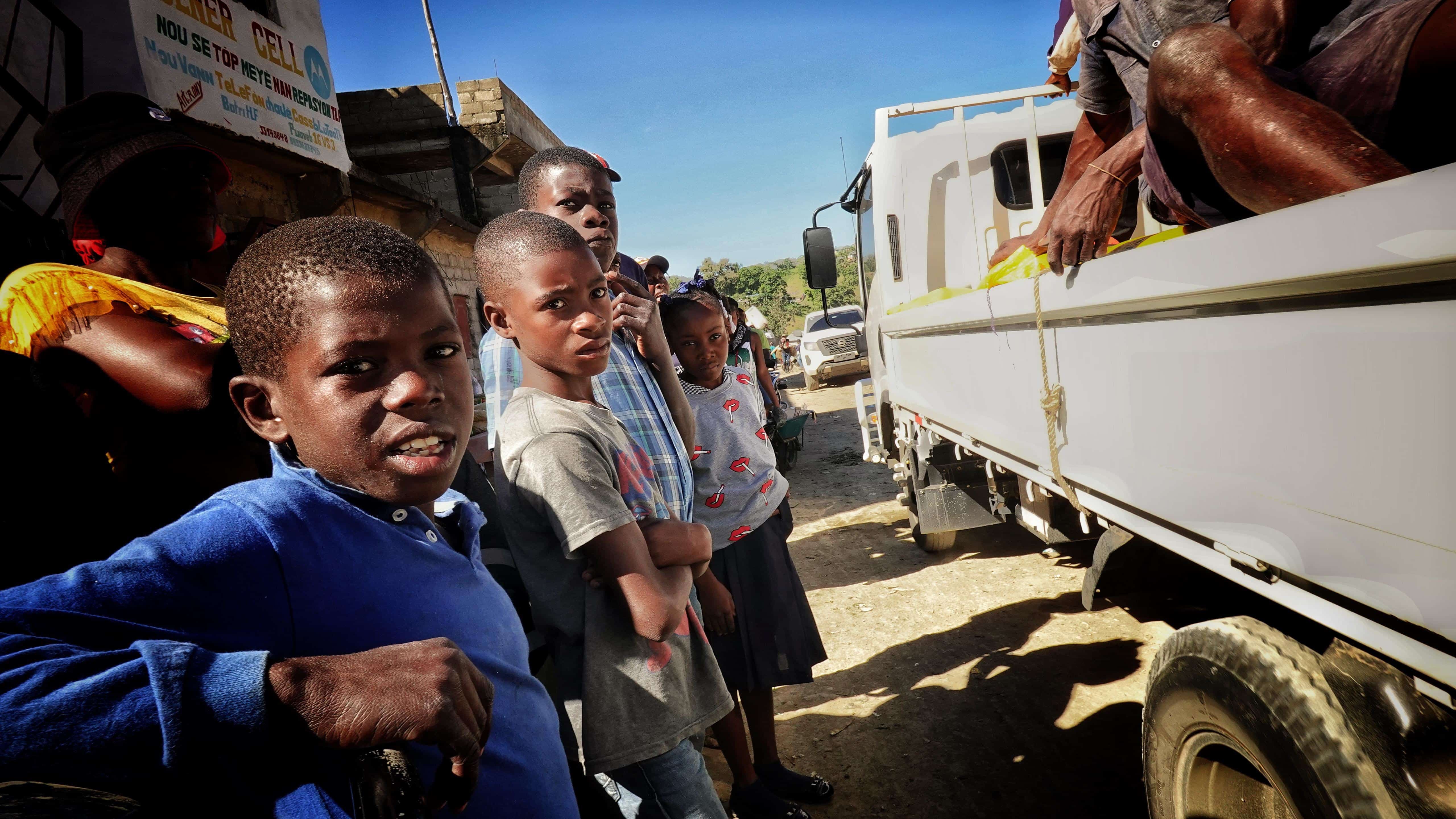 Niños haitianos dejan pasar a una guagua en la avenida principal.