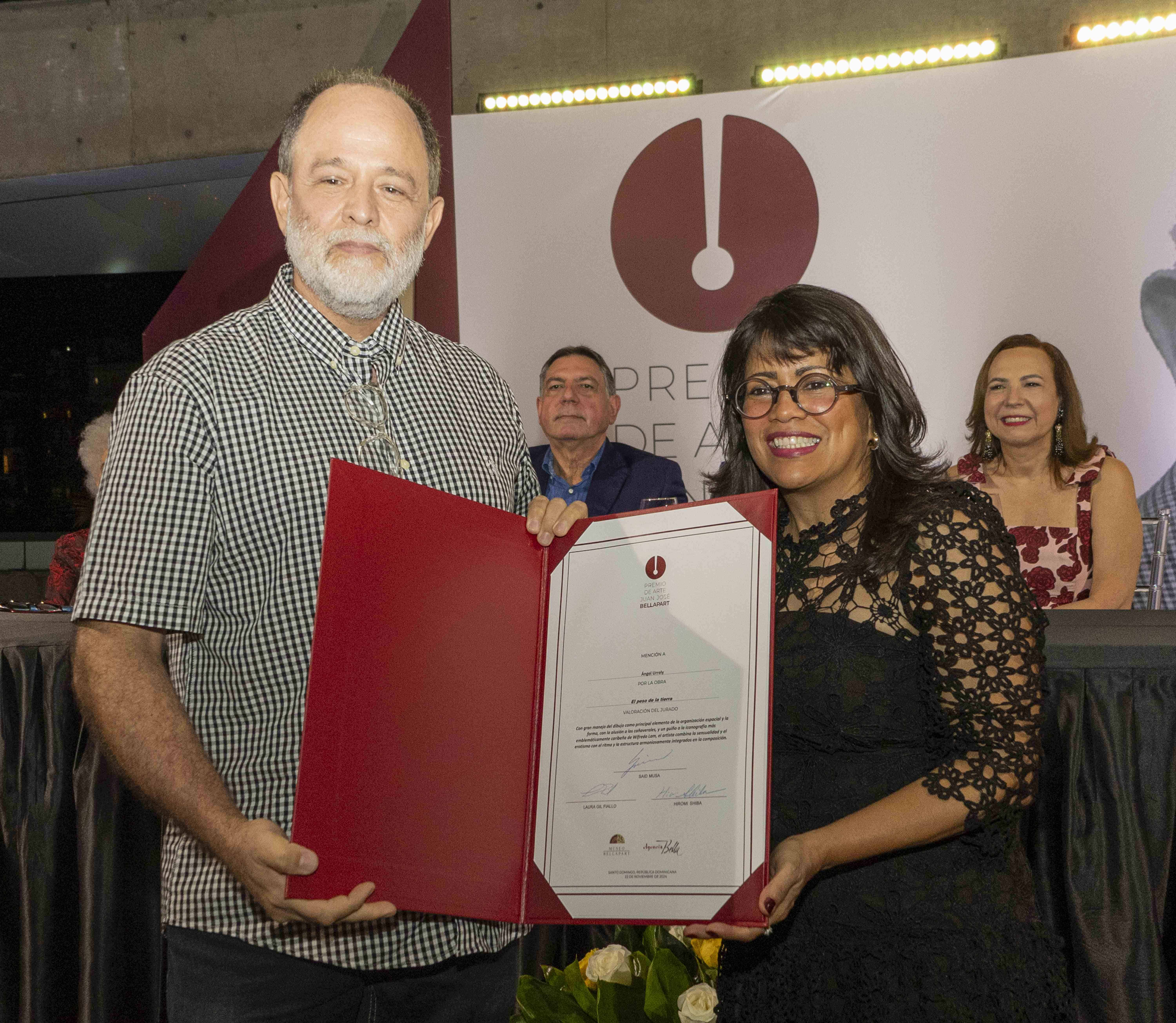 Paula Gómez hace entrega de certificado a Ángel Urrely, por su obra El Peso de la Tierra.