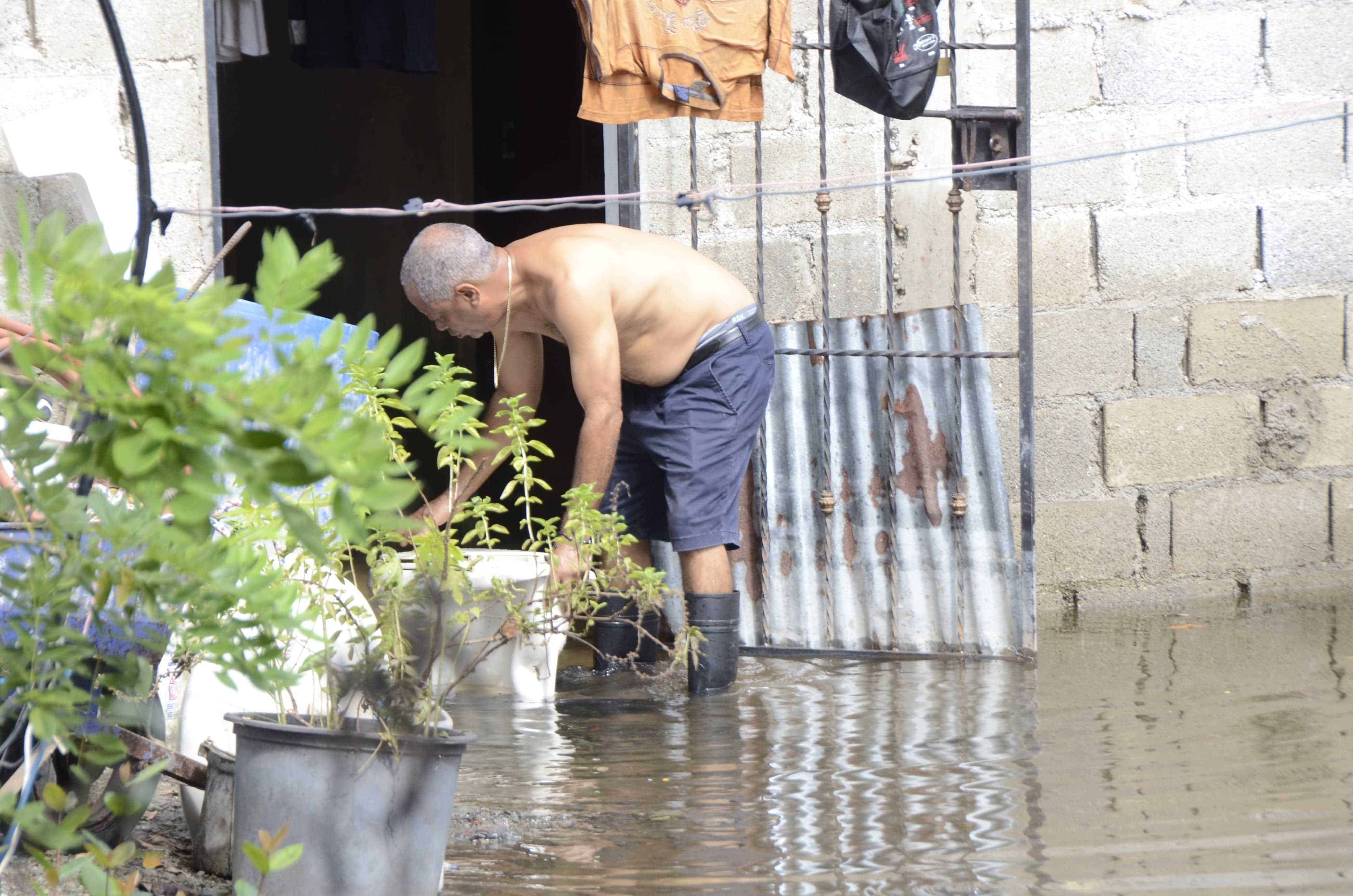 Vista de un hombre al frente de la puerta de su casa totalmente inundada. 