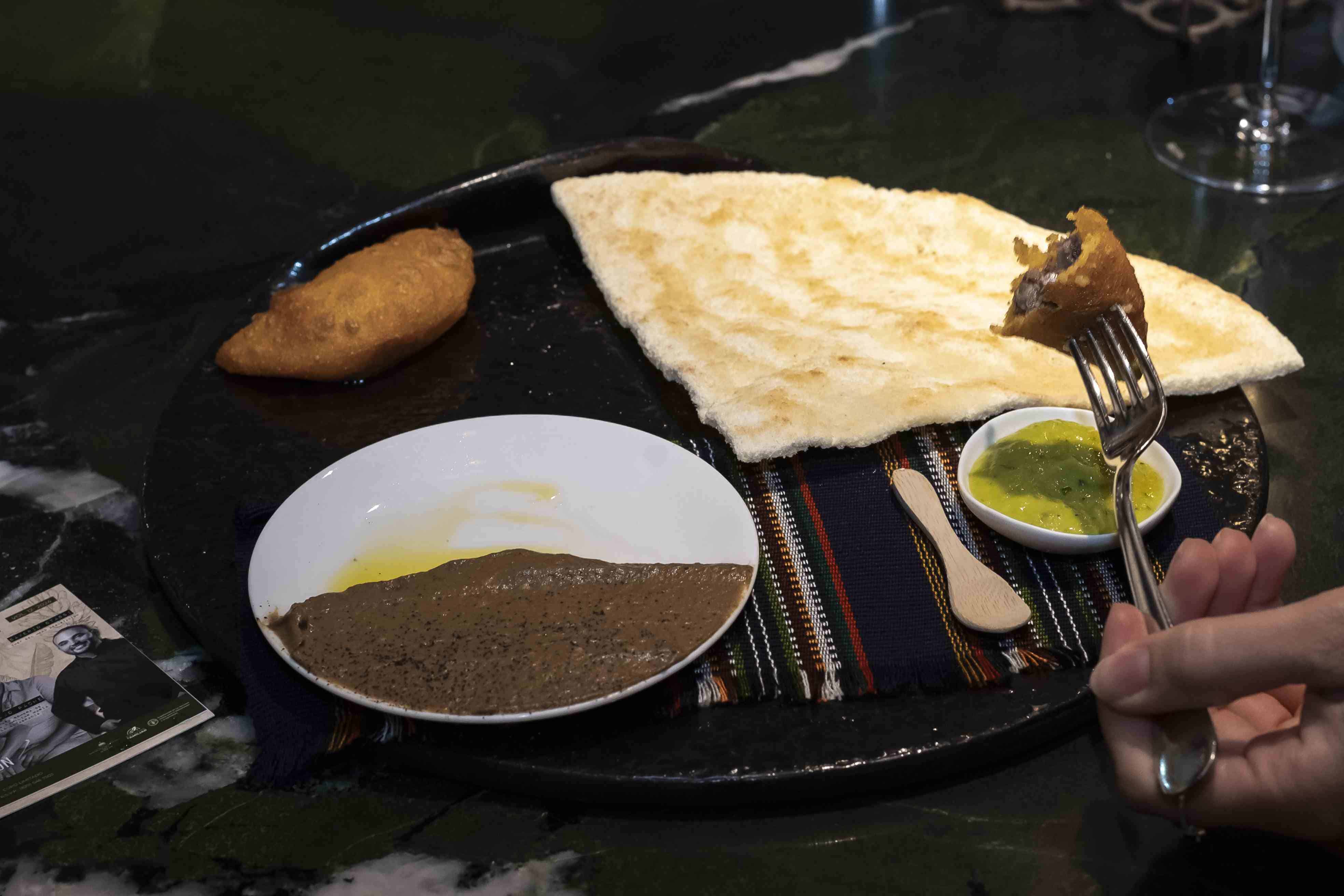 Empanada de maíz, rellena de ropa vieja de chivo, casabe, guacamole.