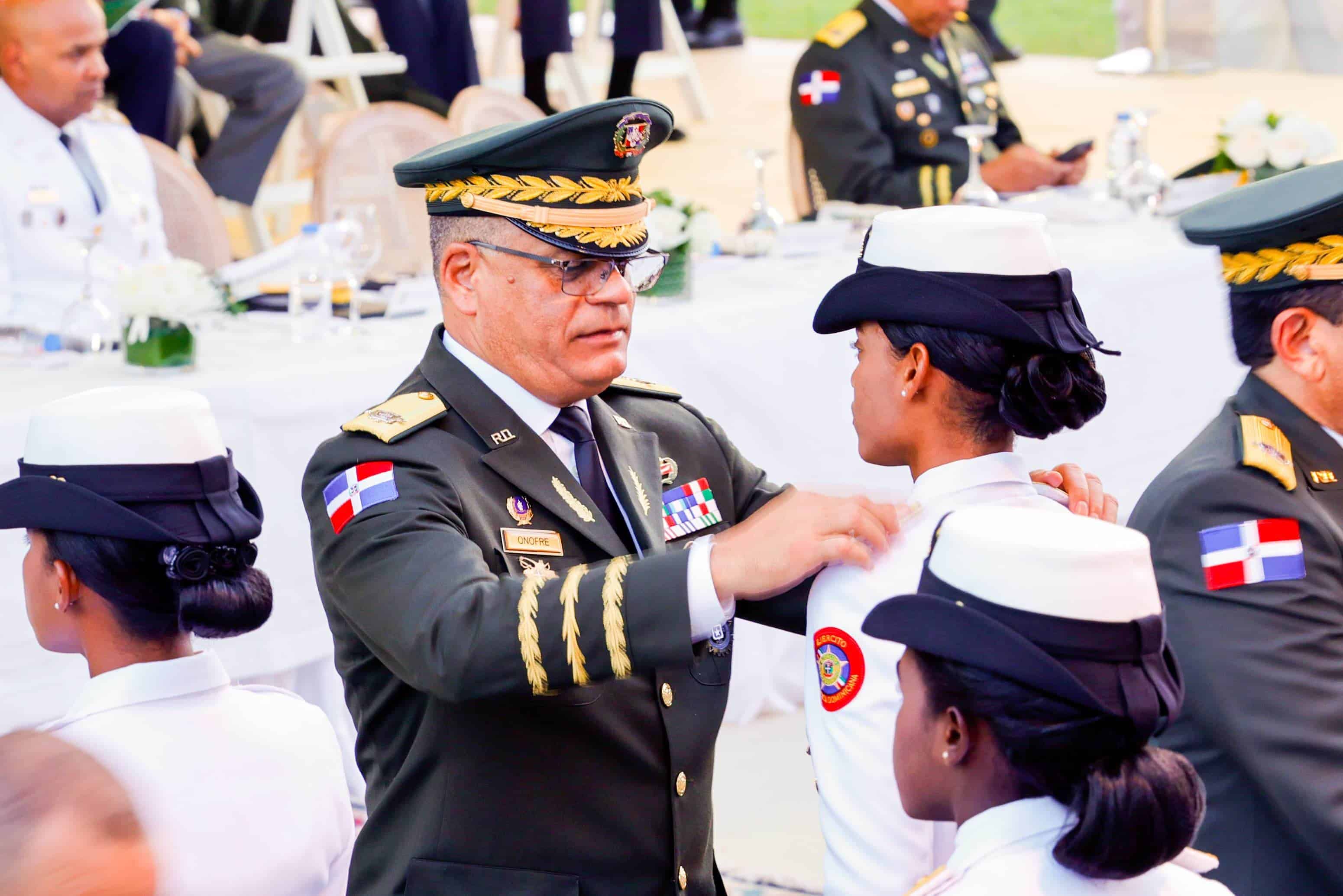 El ministro de Defensa, Carlos Antonio Fernández Onofre, coloca insignia a una de las cadetes que se graduó.