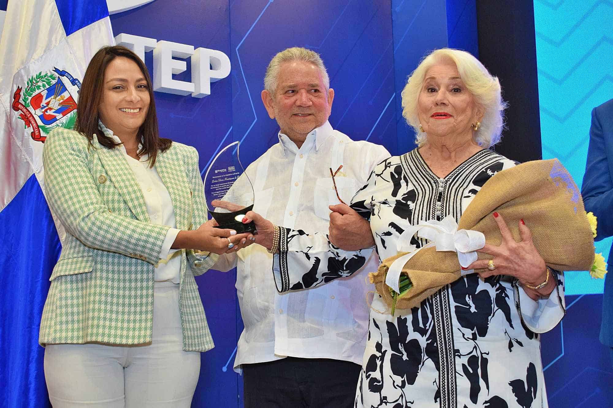 Saskia Roman entrega el reconocimiento a doña Silvia Henriquez de Pou junto a su hermano el viceministro de Mitur Roberto Henriquez.