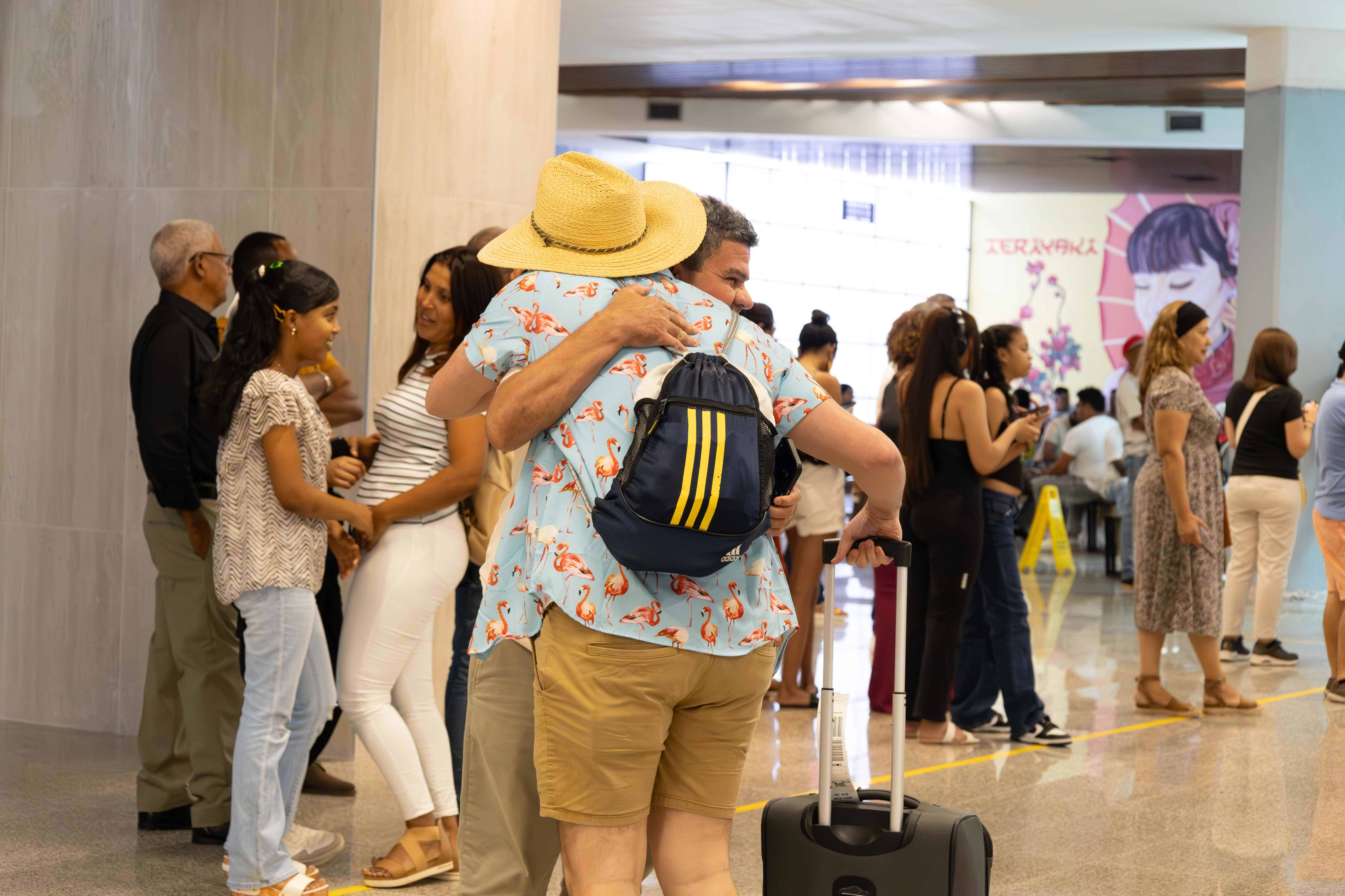 Dos personas se abrazan tras encontrarse a la salida del Aeropuerto Internacional Las Américas (AILA).